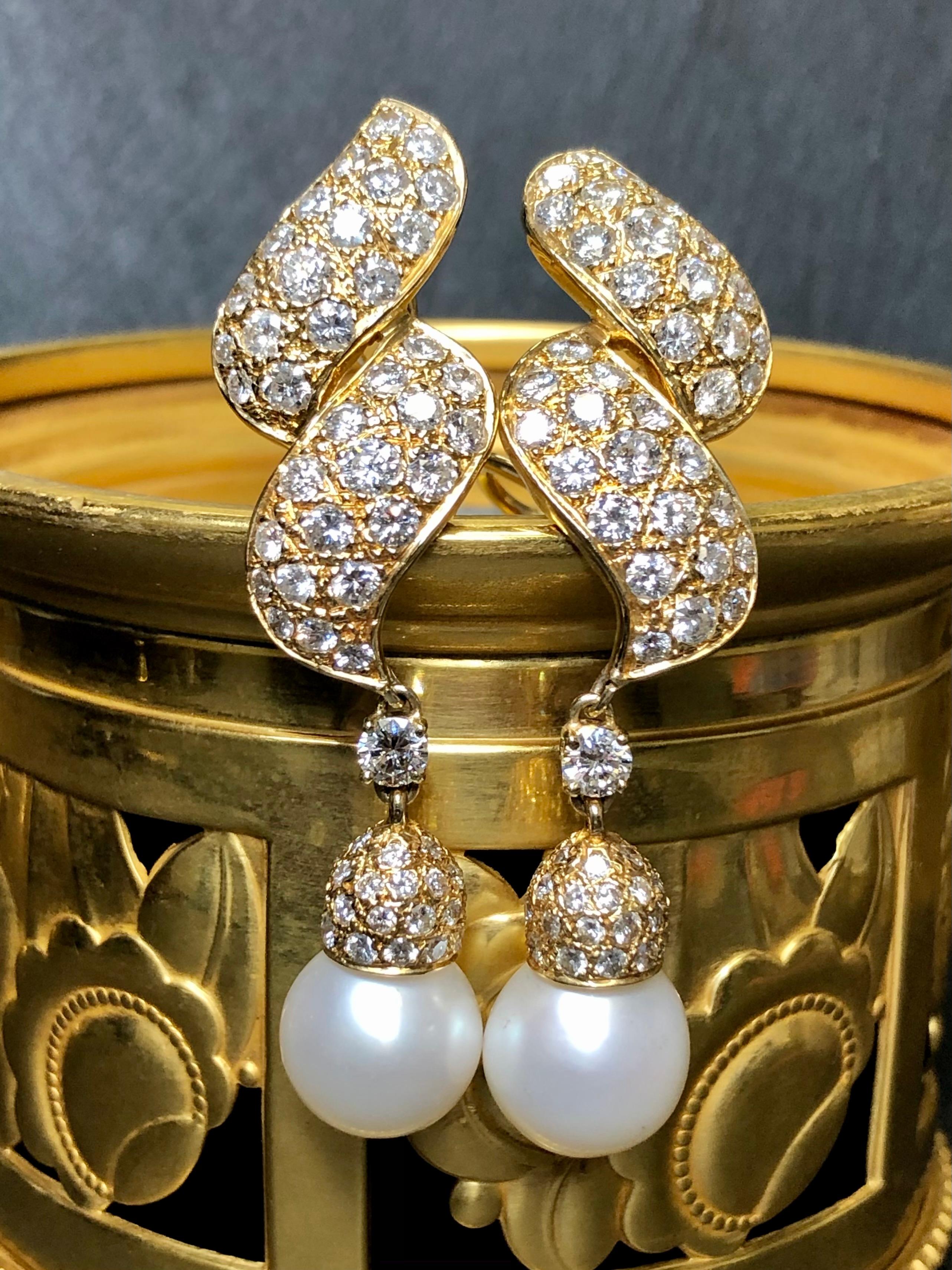 
A fabulous pair of pear drops done in 18K yellow gold and set with approximately 6.65cttw in H-J color Vs1 - Si2 clarity round diamonds. They are finished with 11.50mm and 11.60mm cream colored pearls and are pierced with omega