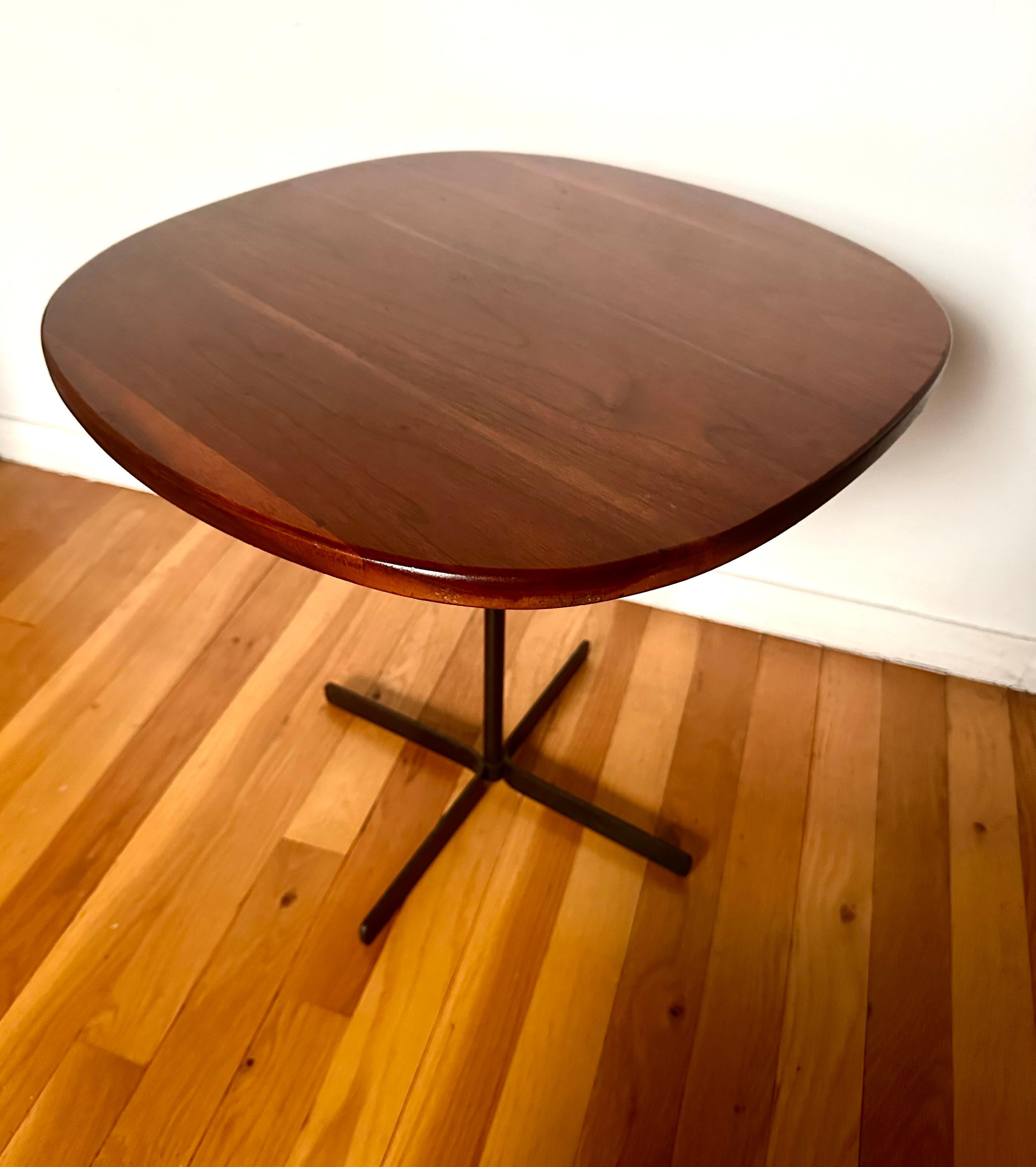 Simple and practical design that effectively conveys the California Craft sensibility through proportion and material.  The rounded square figured-walnut top floats on the slender support over cross base.  Produced for Allan Gould Designs.
