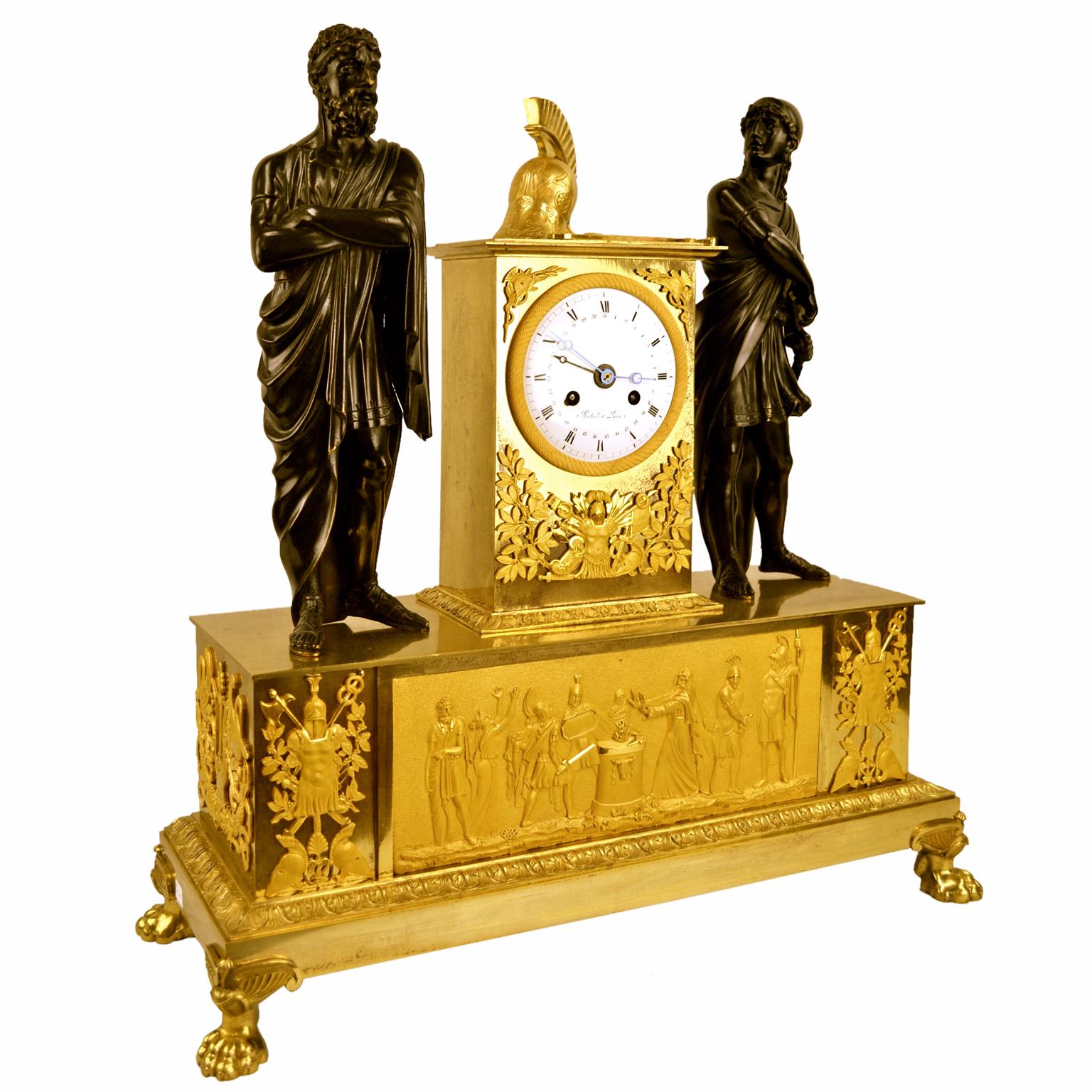 Un bel exemple d'une horloge de cheminée d'époque Empire français qui représente la dispute entre Achille et Agamemnon dans l'Iliade d'Homer. Le coffret est en bronze doré mat et bruni, la base rectangulaire étagée présente une grande frise sur le