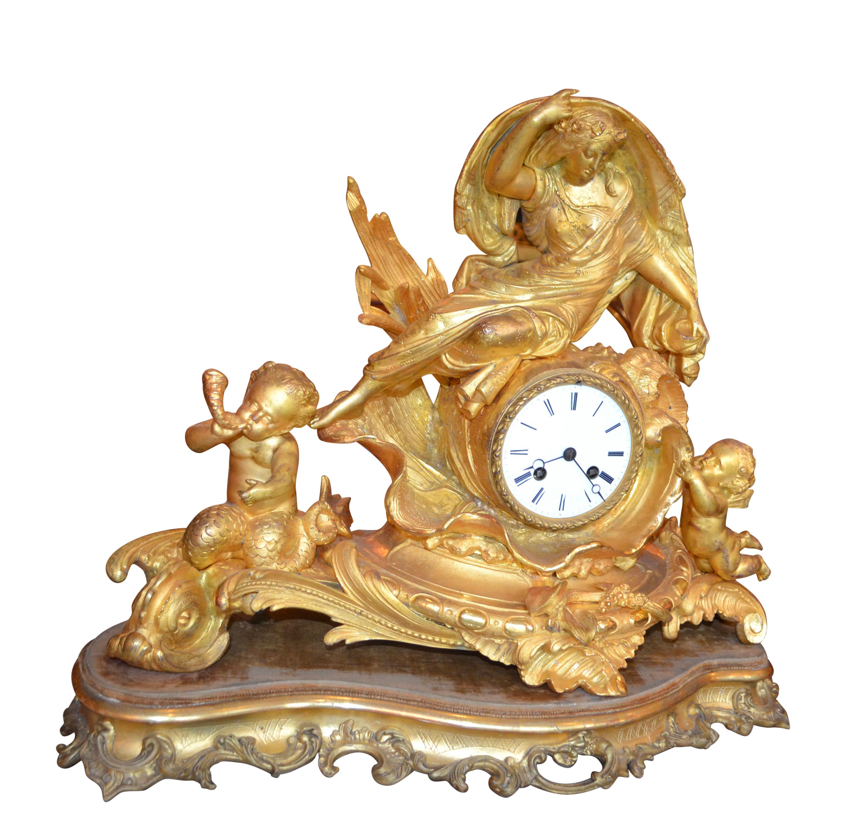 A late 19th century French gilded bronze clock on a gilded wood base. On the left side of the Rococo-style base which resembles rolling waves sits a mermaid like putto riding a dolphin. The right side has another putto reaching up to a large watery
