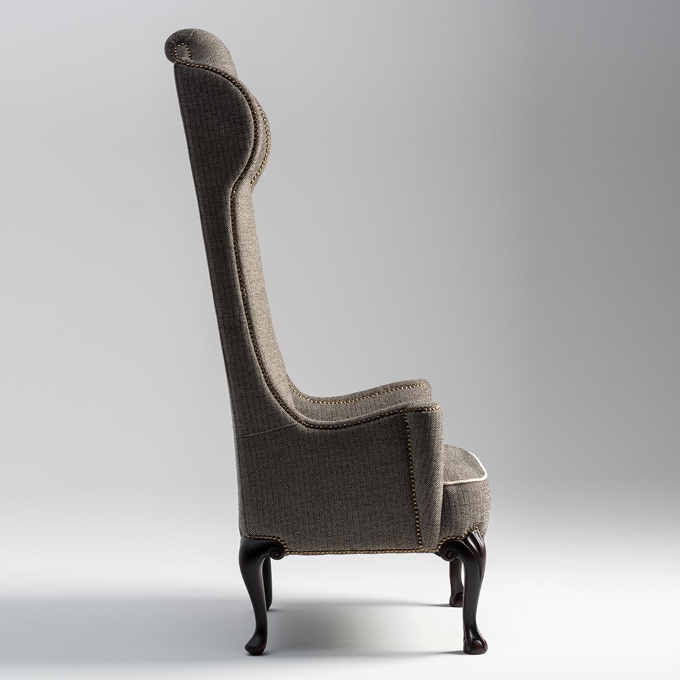 An armchair out of the ordinary with a buttoned back. Exaggerated ears create an enveloping effect. The front legs are finely carved with a soft pattern and with a ball and claw design. Cabriolet hind legs. The fixed seat has a grosgrain border.