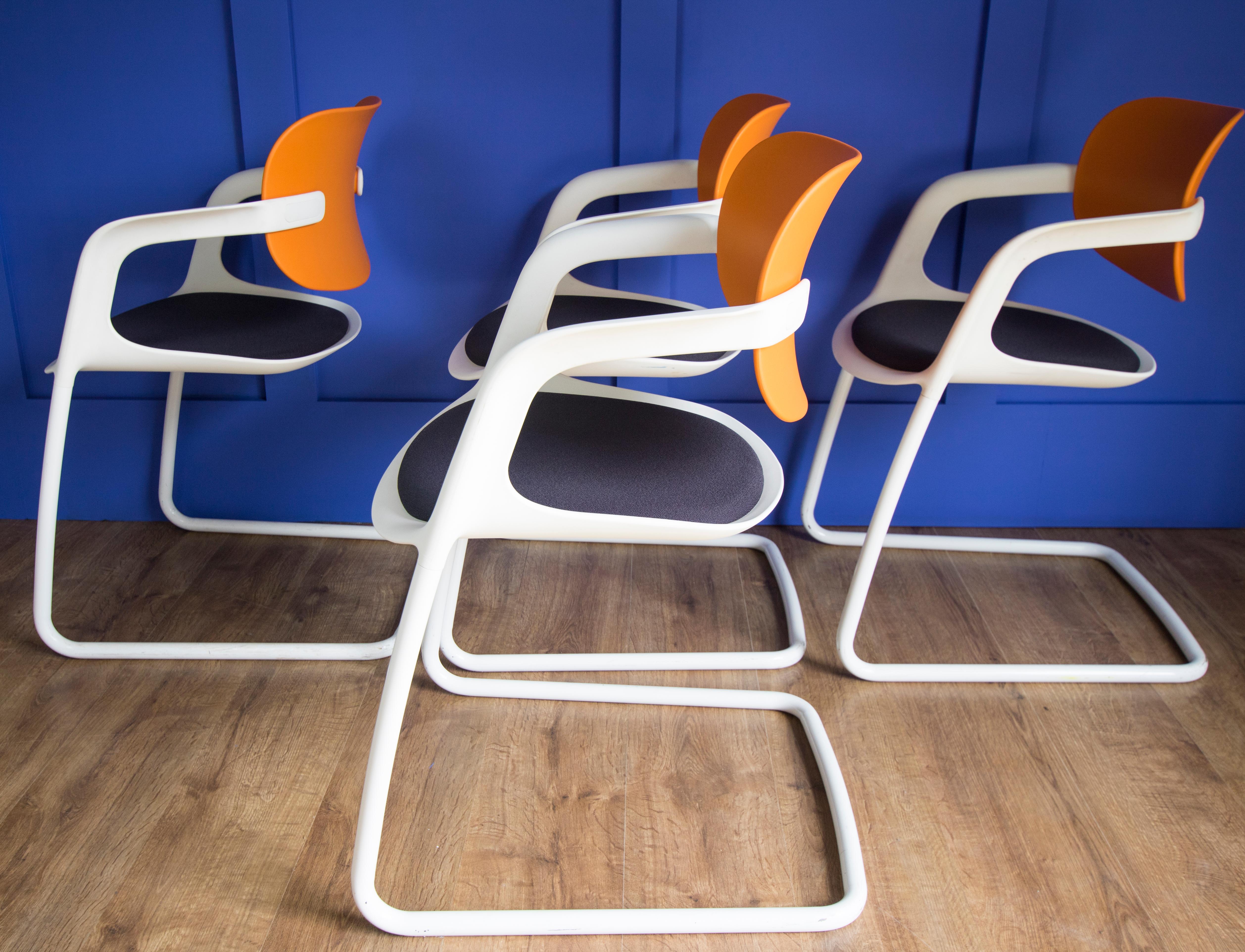 A set of 4 Allermuir Soul dining or office style chairs, with orange backs, white frames, and upholstered navy blue seats, designed by Pearson Lloyd, with maker's marks to the underside. Frames with some marks but structurally completely sound. Very