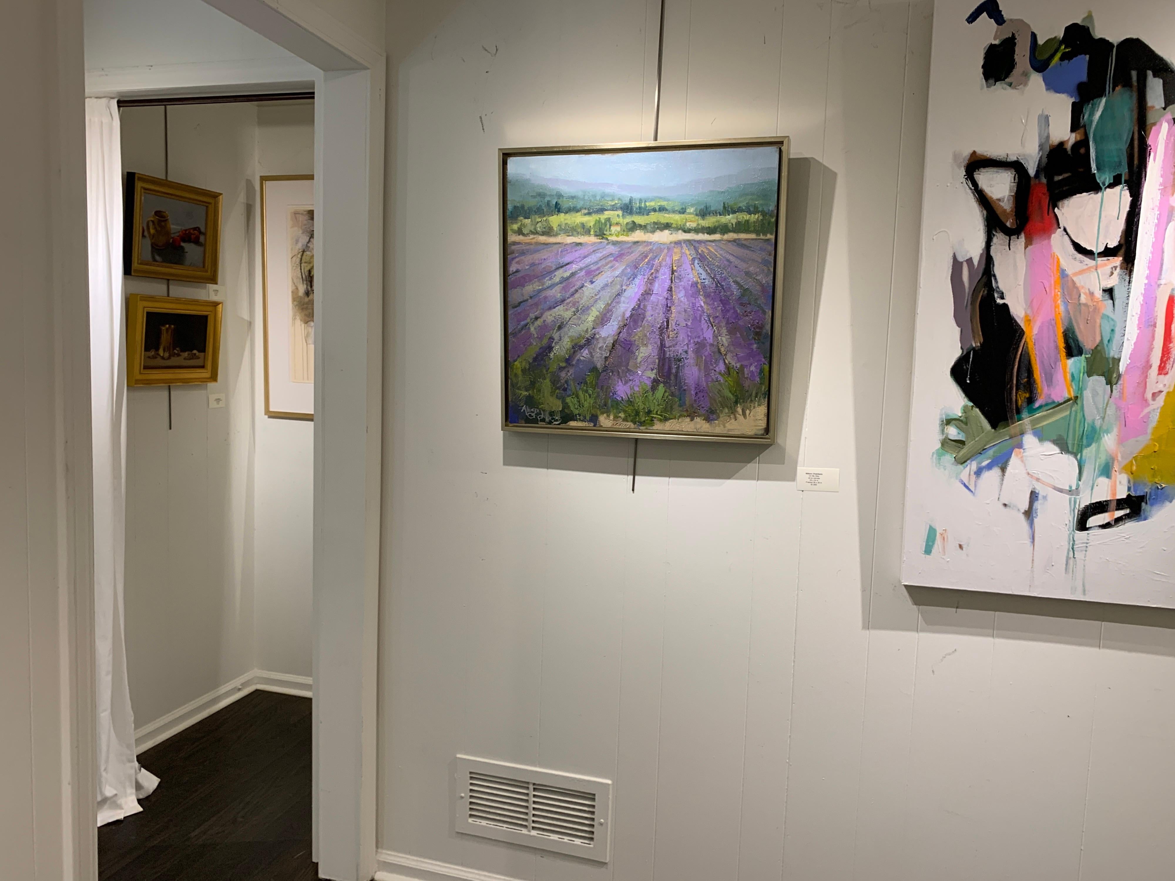'On My Way' is a framed Impressionist oil on canvas painting created by American artist Allison Chambers in 2021. Featuring a palette made of green, blue, neutral and purple tones, the painting depicts a vineyard leading our eye to the purple-shaded