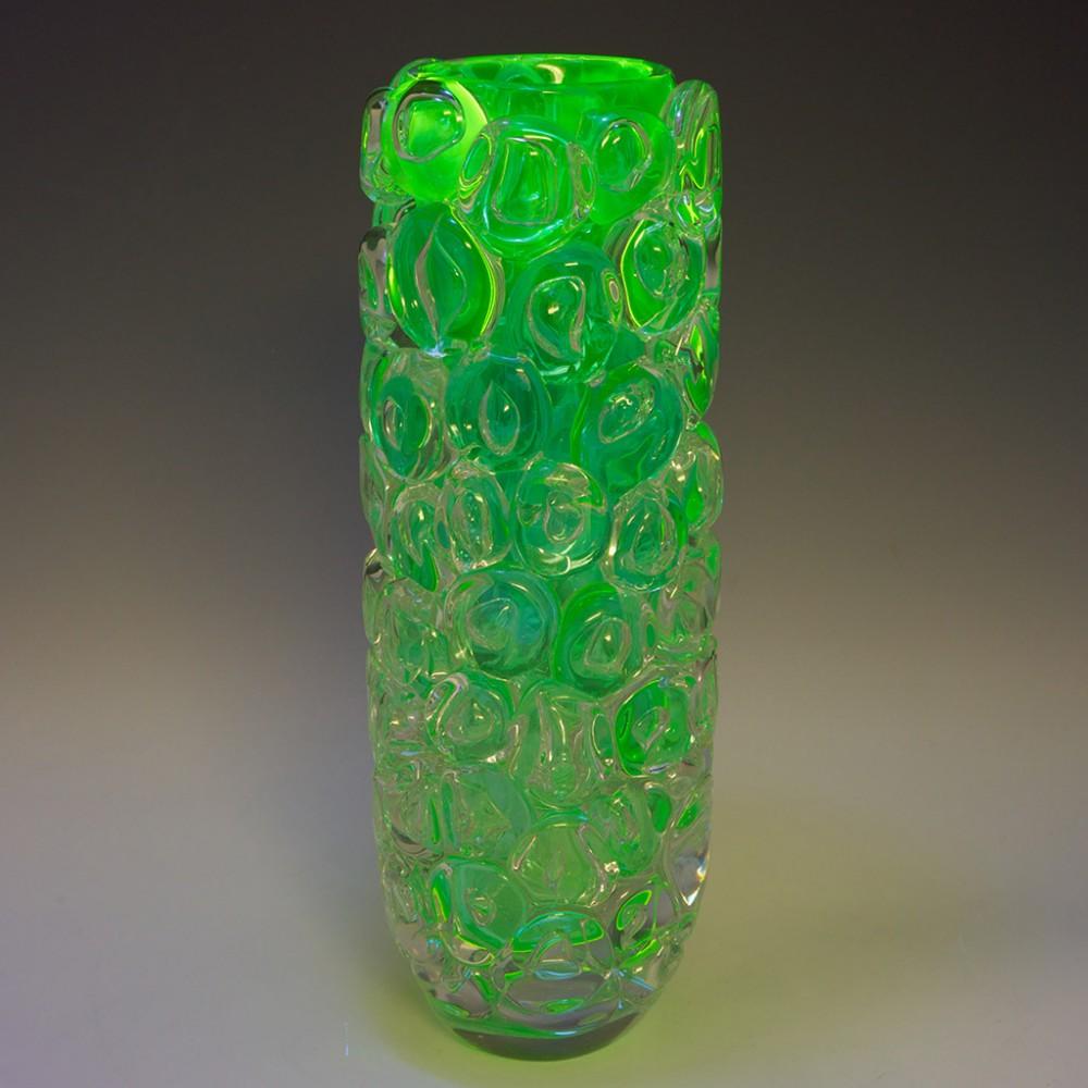 Heading : Allister Malcolm Luminescent Aqua Bubble Wrap Cylindrical Vase
Date : 2023
Origin : Stourbridge
Bowl Features : Aquamarine internal transitioning to clear with a fine coating of uranium. Applied disc shaped prunts with trapped air