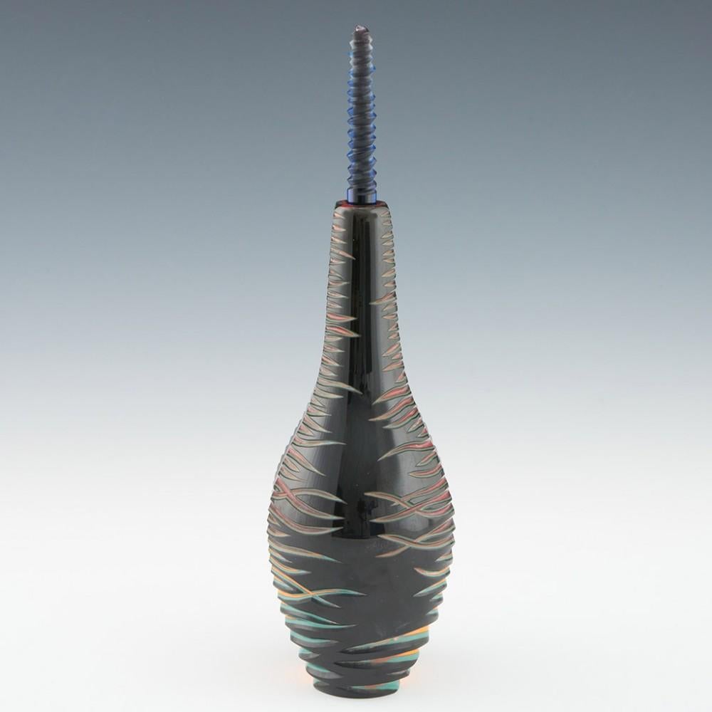 Heading :  Malcolm pod bottle
Date : 2023
Origin : Stourbridge, England
Colour : Polycrhome
Body : In the form of a seed pod, the black outer layer cut away to reveal turquoise, orange, clear and ruby glass with naturalistic cuts.
Base : Signed