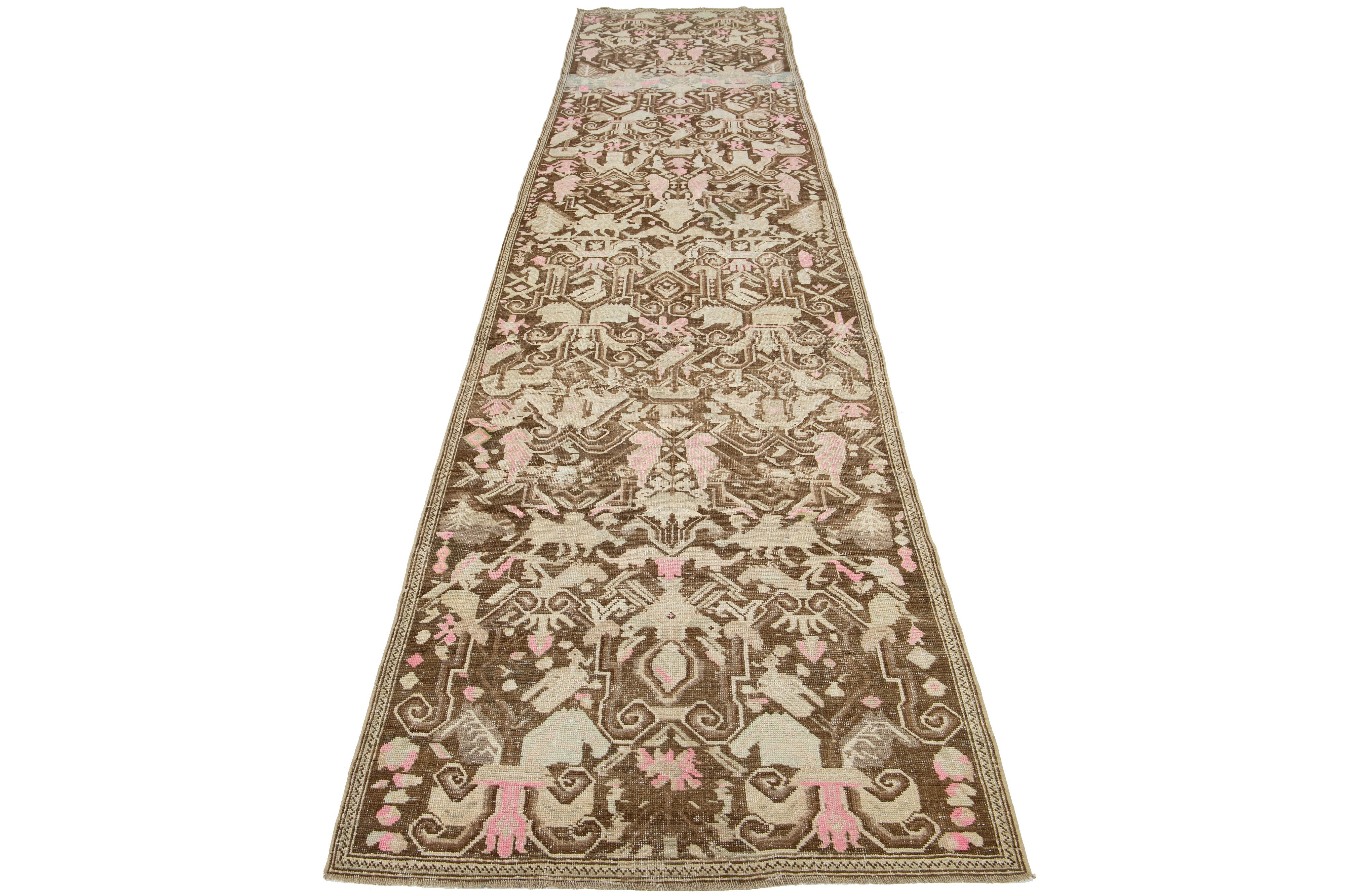 This is a beautiful Antique Karabagh hand-knotted wool runner with a brown-colored field. The rug showcases accents of beige and pink in a stunning all-over design.

This rug measures 3'5