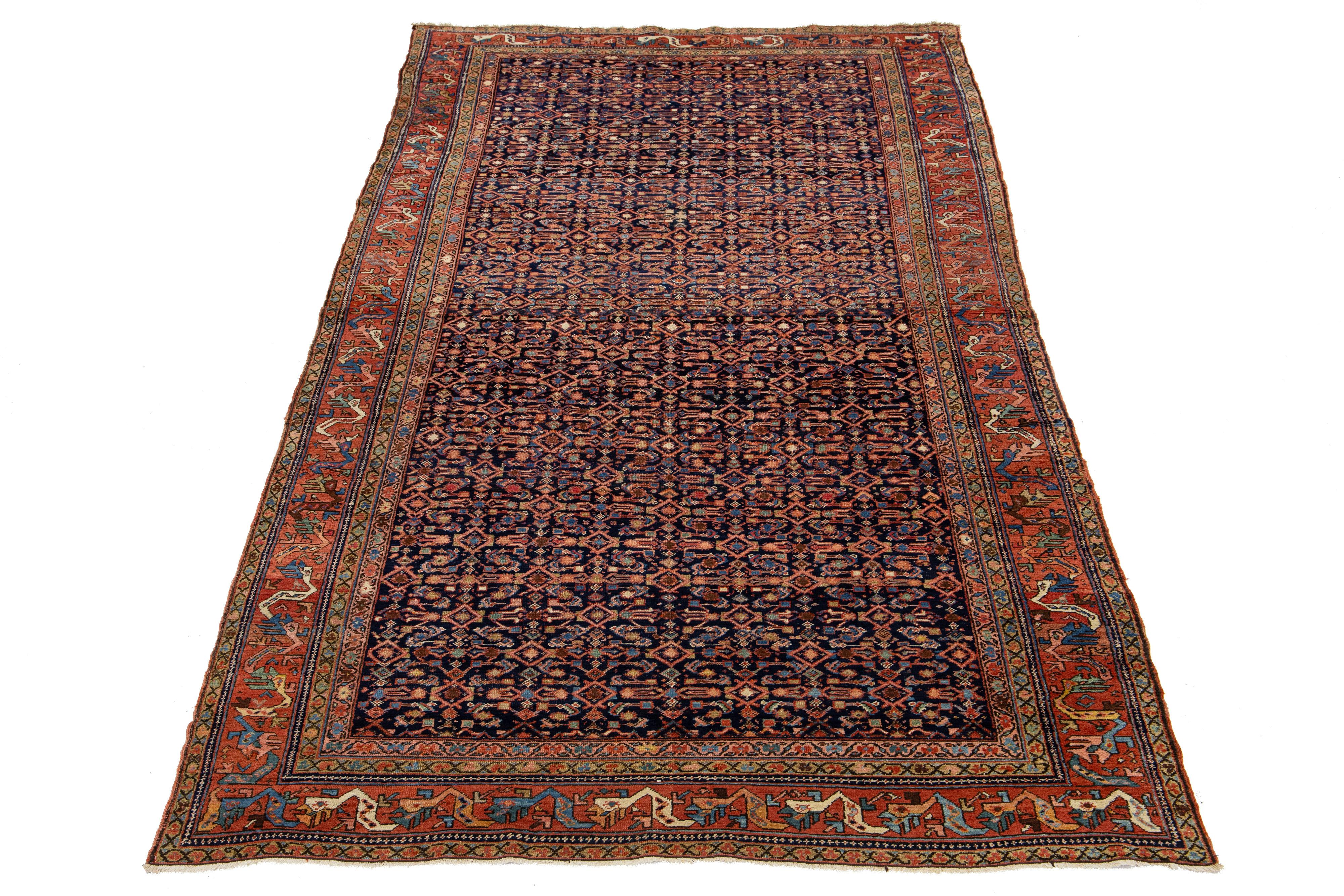 This is a handmade Persian Malayer rug from the 20th century. It features a navy blue field with multicolor accents throughout the geometric floral pattern.

This rug measures 7'4