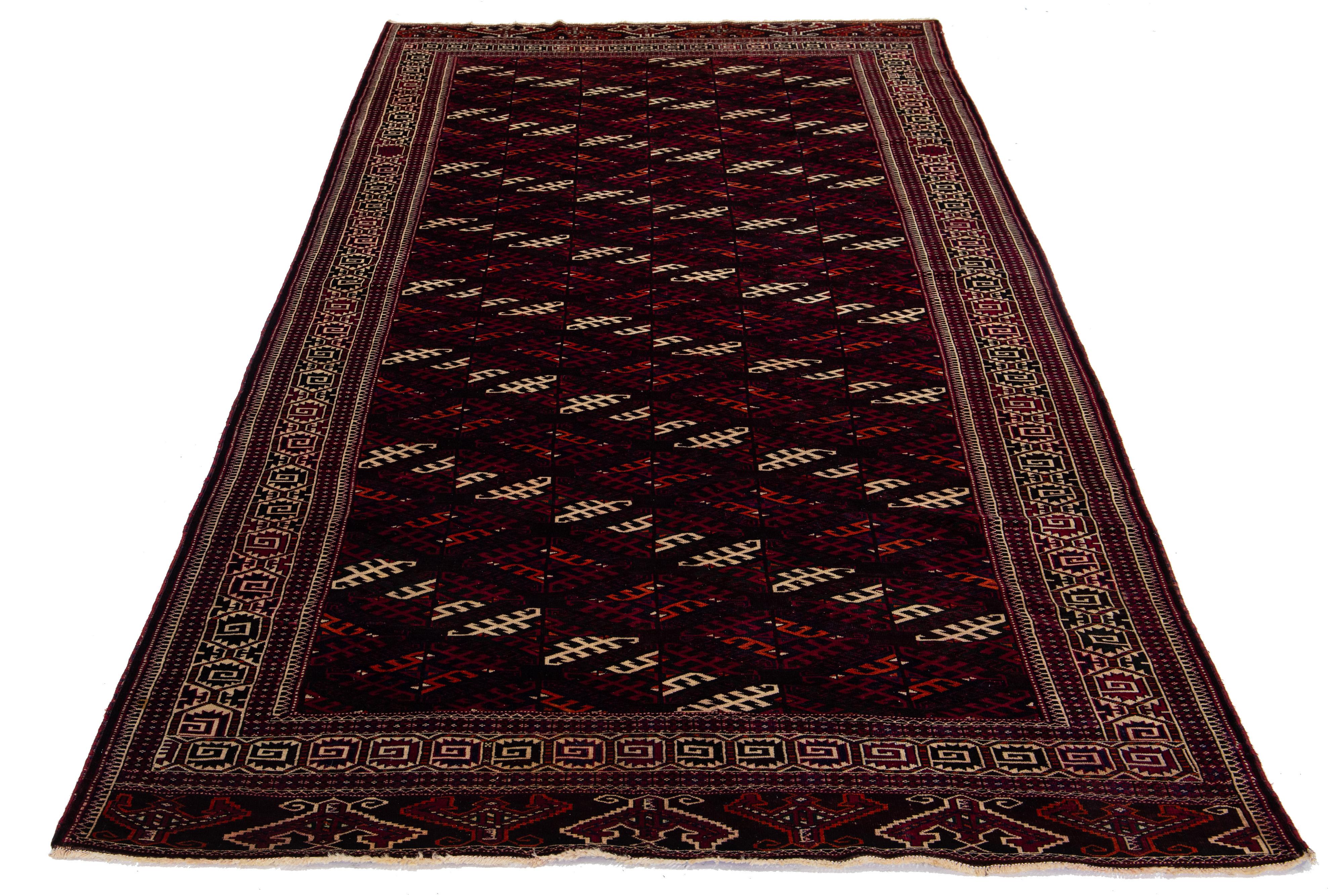 Un tappeto afgano vintage in lana annodato a mano con un motivo geometrico nei toni del blu, del beige e dell'arancione su uno sfondo bordeaux.

Questo tappeto misura 6'10' x 13'1