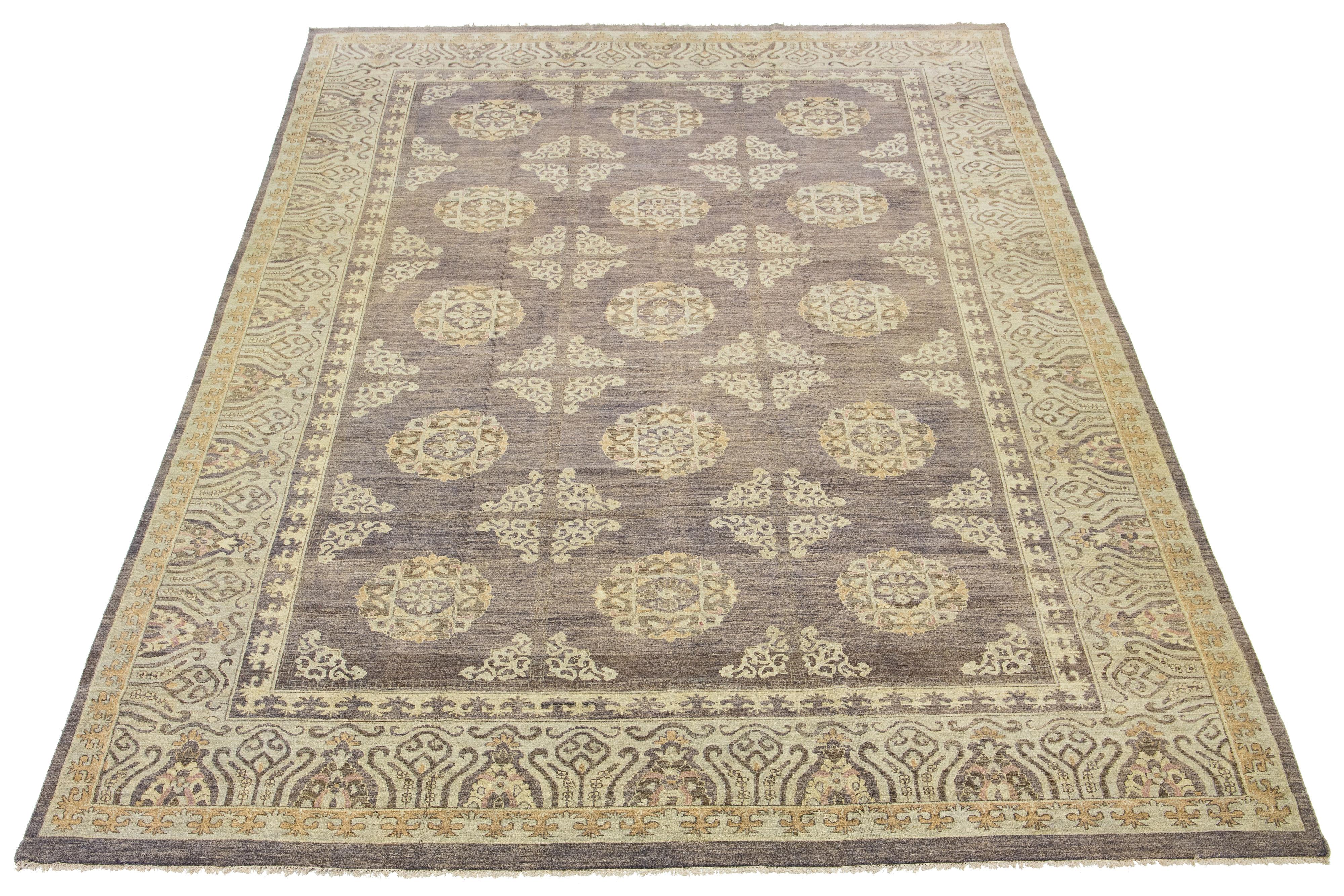 This is an oversized contemporary Khotan wool rug from India. The design showcases a brown and blue field with beige, cream-colored patterns. These include eye-catching floral patterns.

This rug measures 12' x 17'9