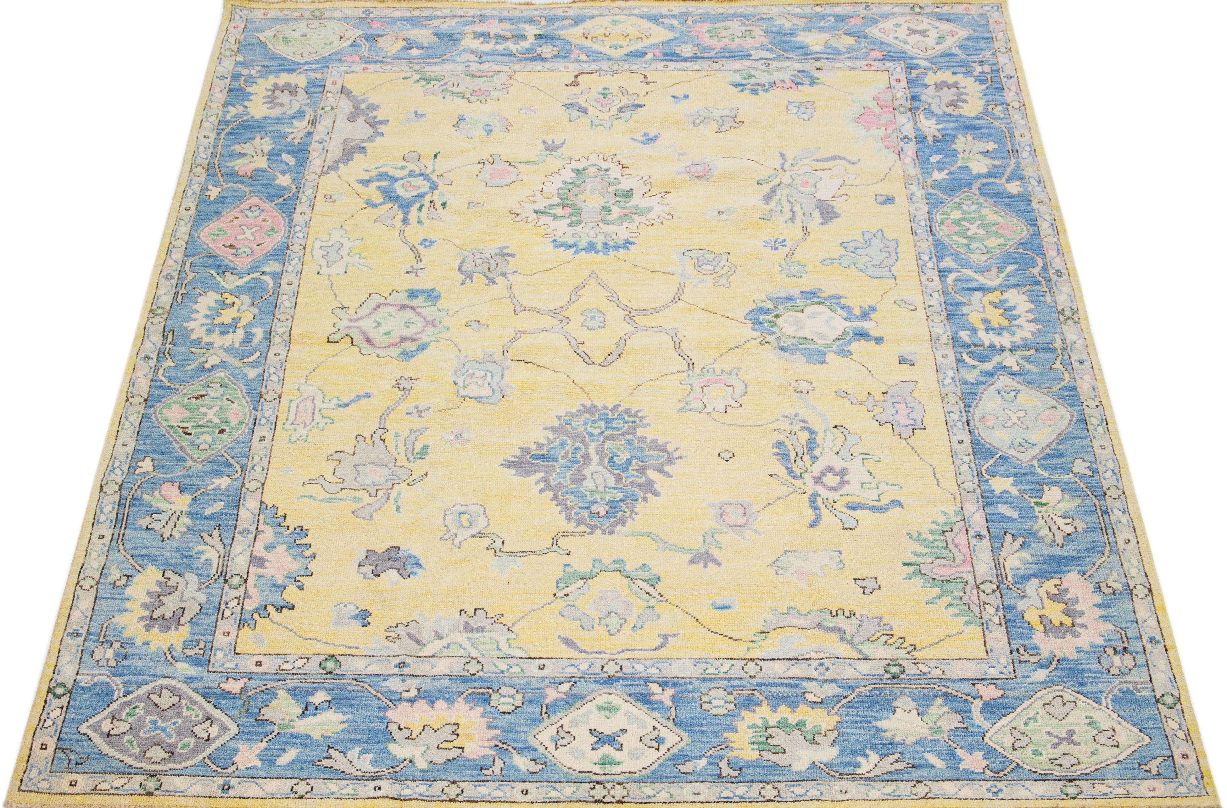 Beautiful modern Oushak hand knotted wool rug with a yellow color field. This Turkish rug has a blue frame with rose, gray, and green accent colors in a gorgeous all-over floral design. This timeless piece is sure to be the focal point of any room