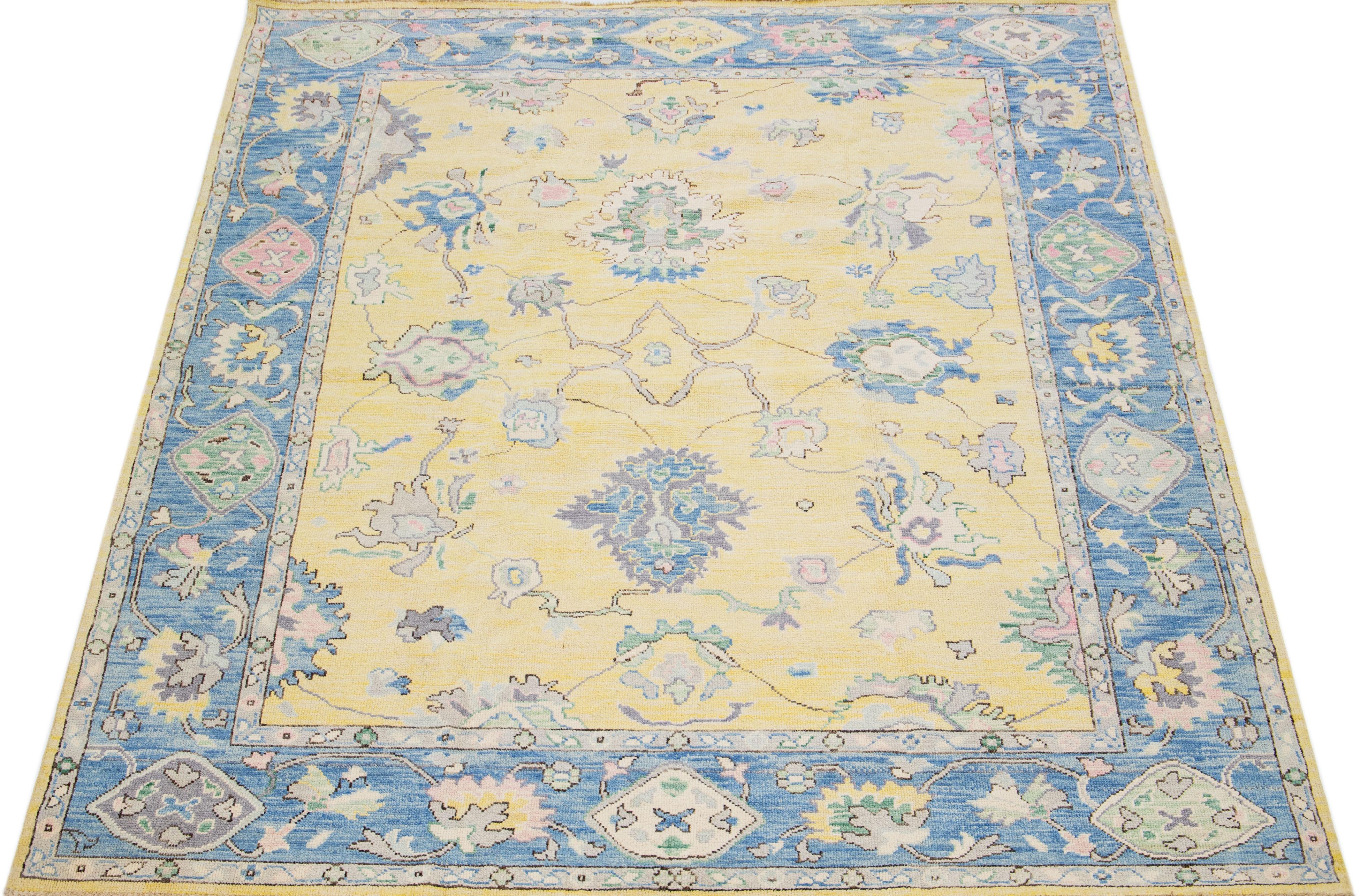 Magnifique tapis moderne Oushak en laine nouée à la main avec un champ de couleur jaune. Ce tapis turc a un cadre bleu avec des couleurs d'accentuation rose, gris et vert dans un magnifique motif floral. Cette pièce intemporelle est sûre d'être le