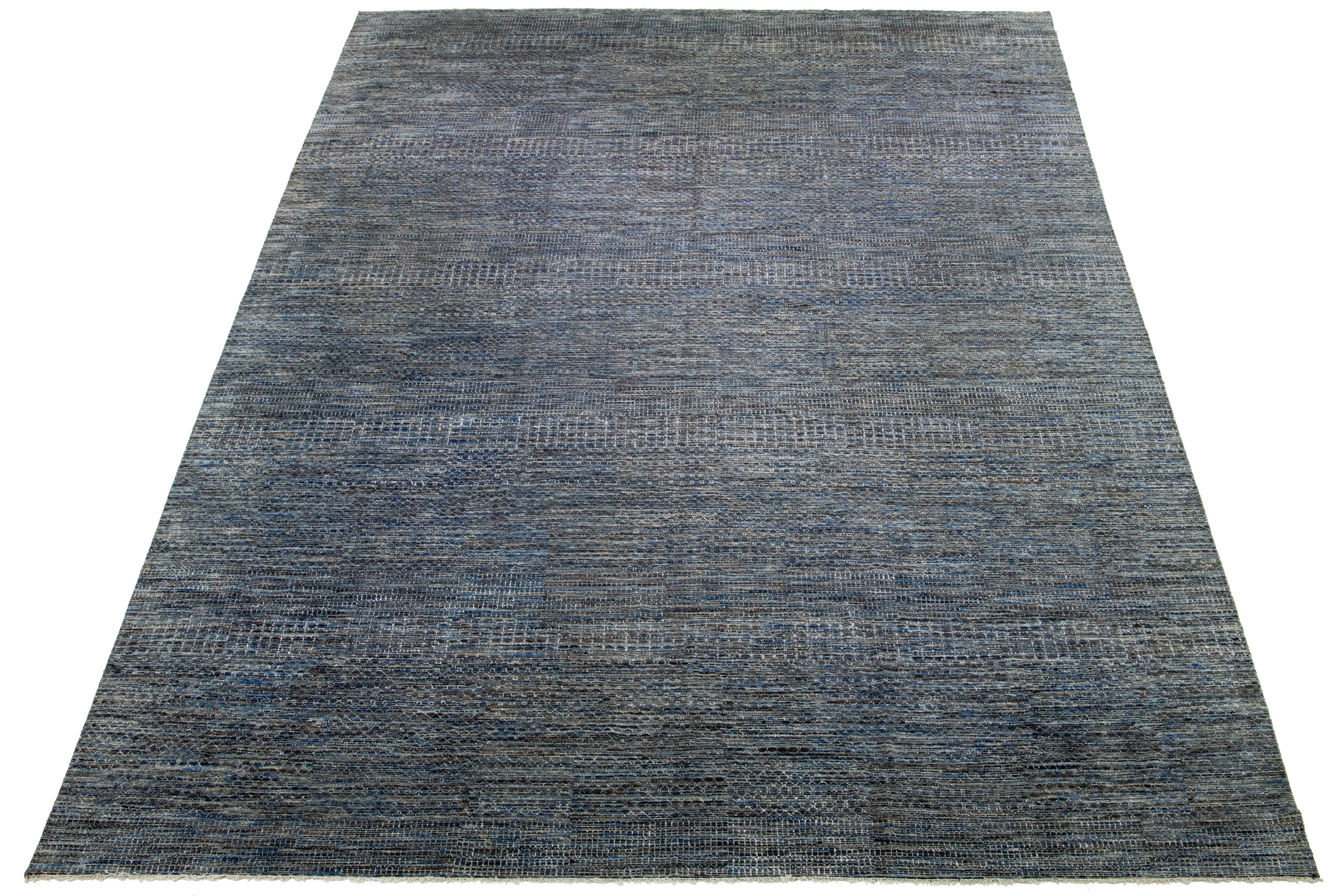 This beautiful hand-knotted Savannah wool rug features a stunning contemporary design, showcasing a meticulously crafted gray field with intricate geometric patterns in blue, ivory, and brown accents.

This rug measures 16'3