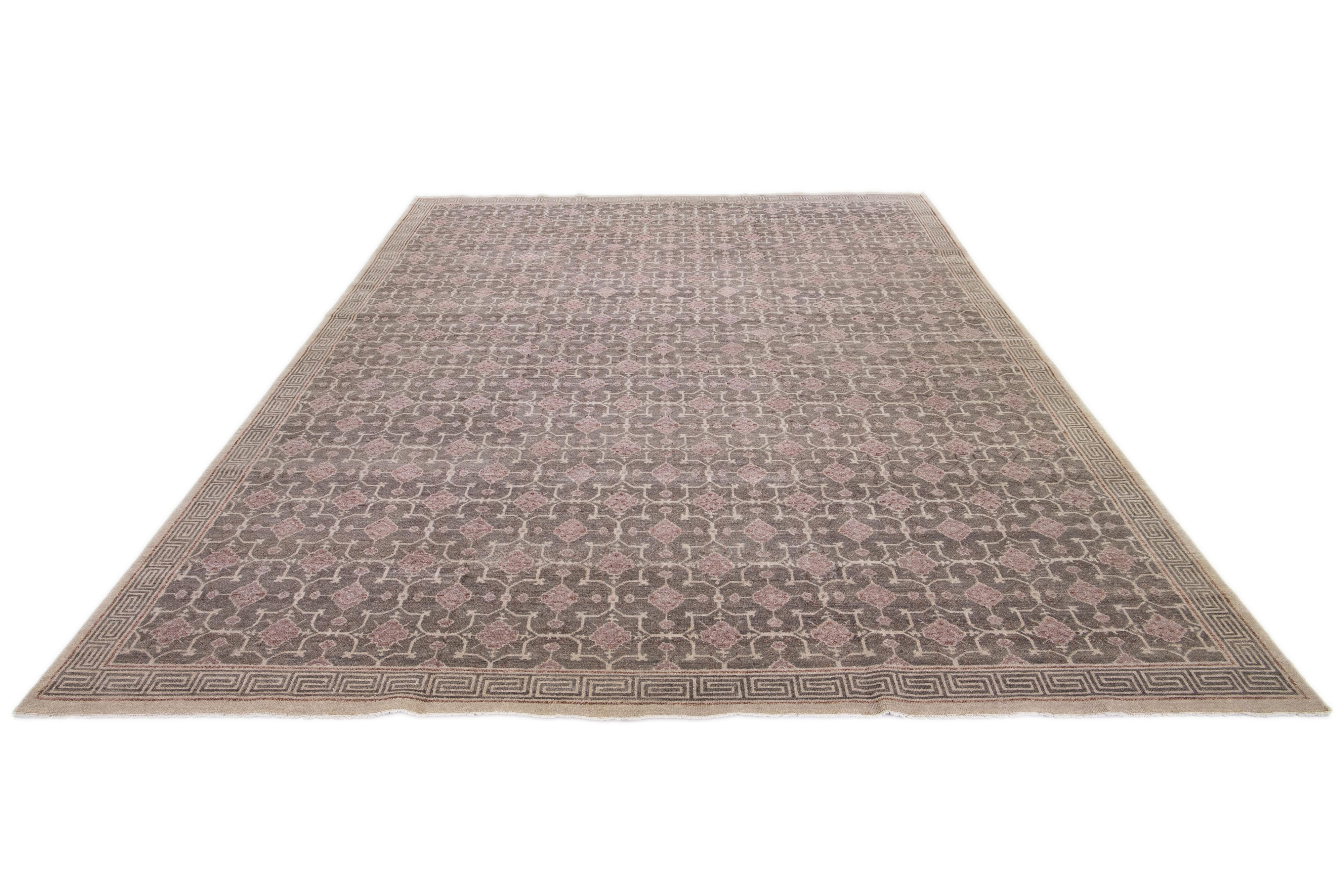 A Khotan wool rug In a gray color field with interconnected rosette designs. This hand-knotted modern piece has beige and brown accents that complement the design.

This rug measures 11'10