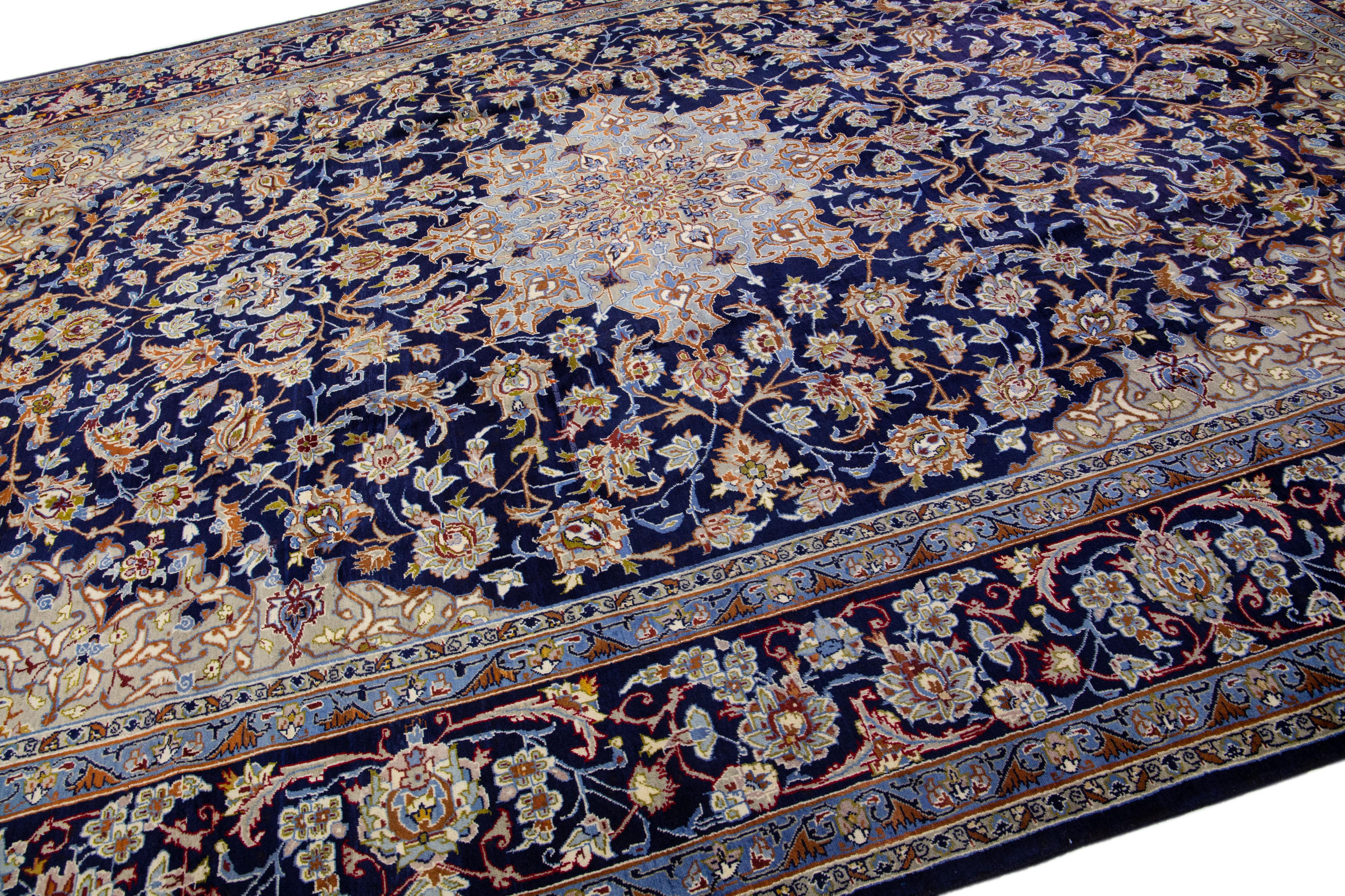 Beautiful Persian Isfahan hand-knotted natural wool rug with a navy blue color field. This piece has a designed frame with rust, beige, and light blue accents in an all-over medallion floral design.

This rug measures: 11'2