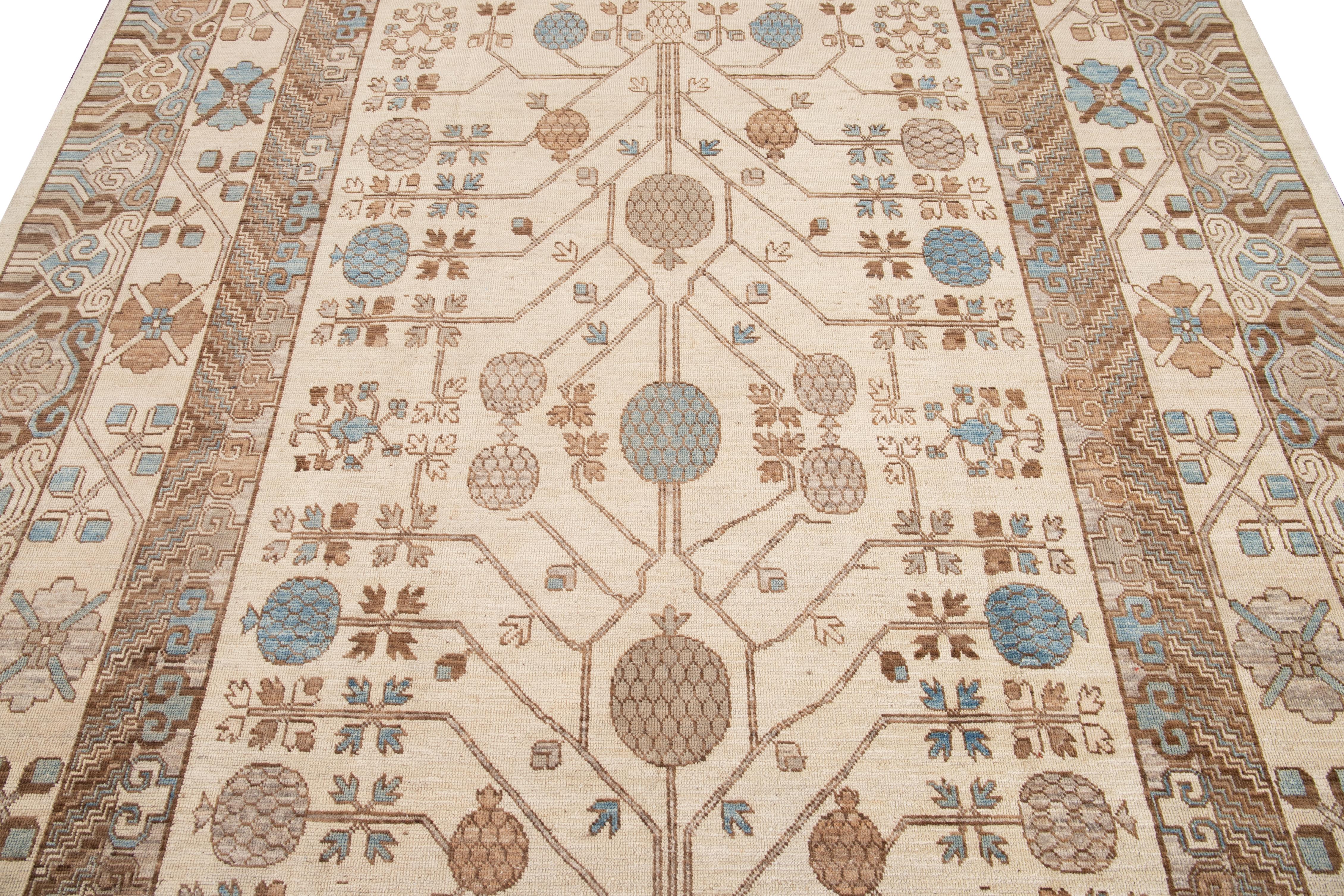 Dieser Teppich aus Khotan-Wolle zeichnet sich durch ein wunderschönes beiges Farbfeld aus, das mit exquisiten, miteinander verbundenen Rosettenmustern von Granatäpfeln verziert ist. Die aufwendige handgeknüpfte Verarbeitung verleiht diesem Stück