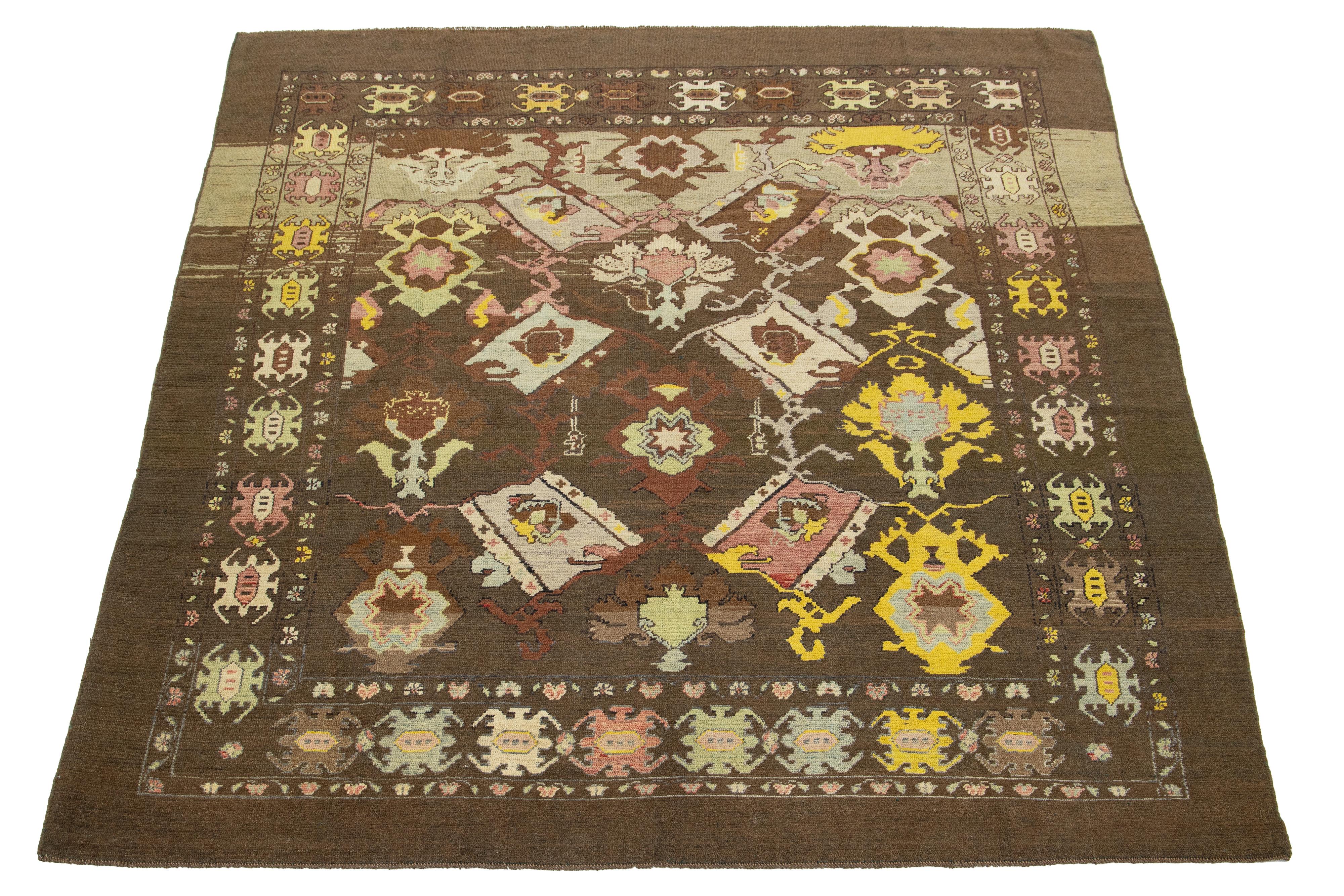 This is a beautiful room-size modern hand-knotted wool rug with a brown base. It is part of Apadana's Revival Collection and features yellow, peach, beige, and green accents alongside a stunning geometric botanical floral design.

This rug measures