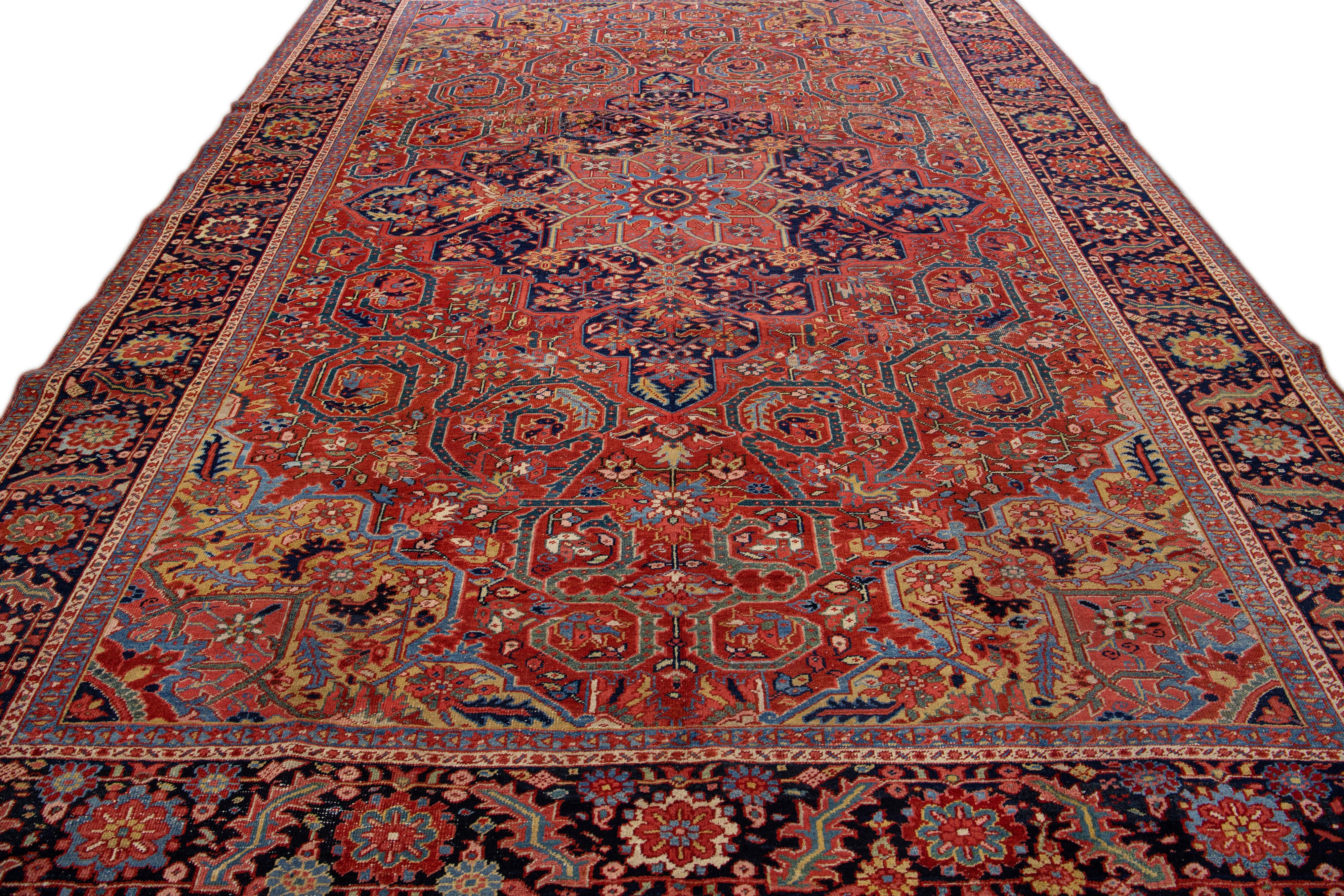 Beautiful antique Heriz hand-knotted wool rug with a red color field. This Persian rug has a navy-blue designed frame and multicolor accents in a gorgeous medallion floral design.

This rug measures: 9'9