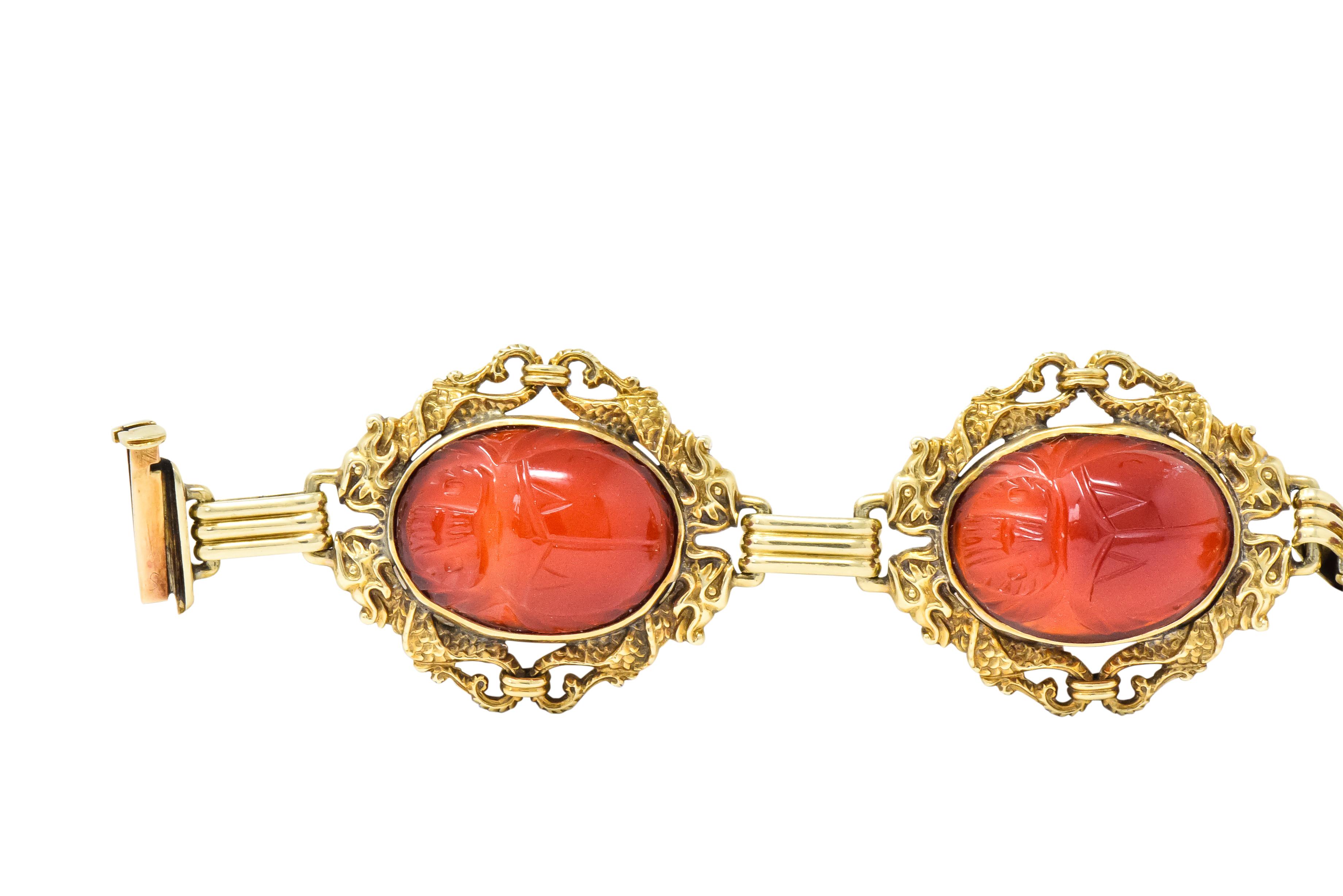 Set with five oval scarab carved carnelian cabochons, measuring approximately 20. x 15.0 mm, deep brownish orange, matched

Bezel set with detailed dragon motif surrounds and ribbed gold spacer links  

Concealed clasp, stamped 14K and maker's mark
