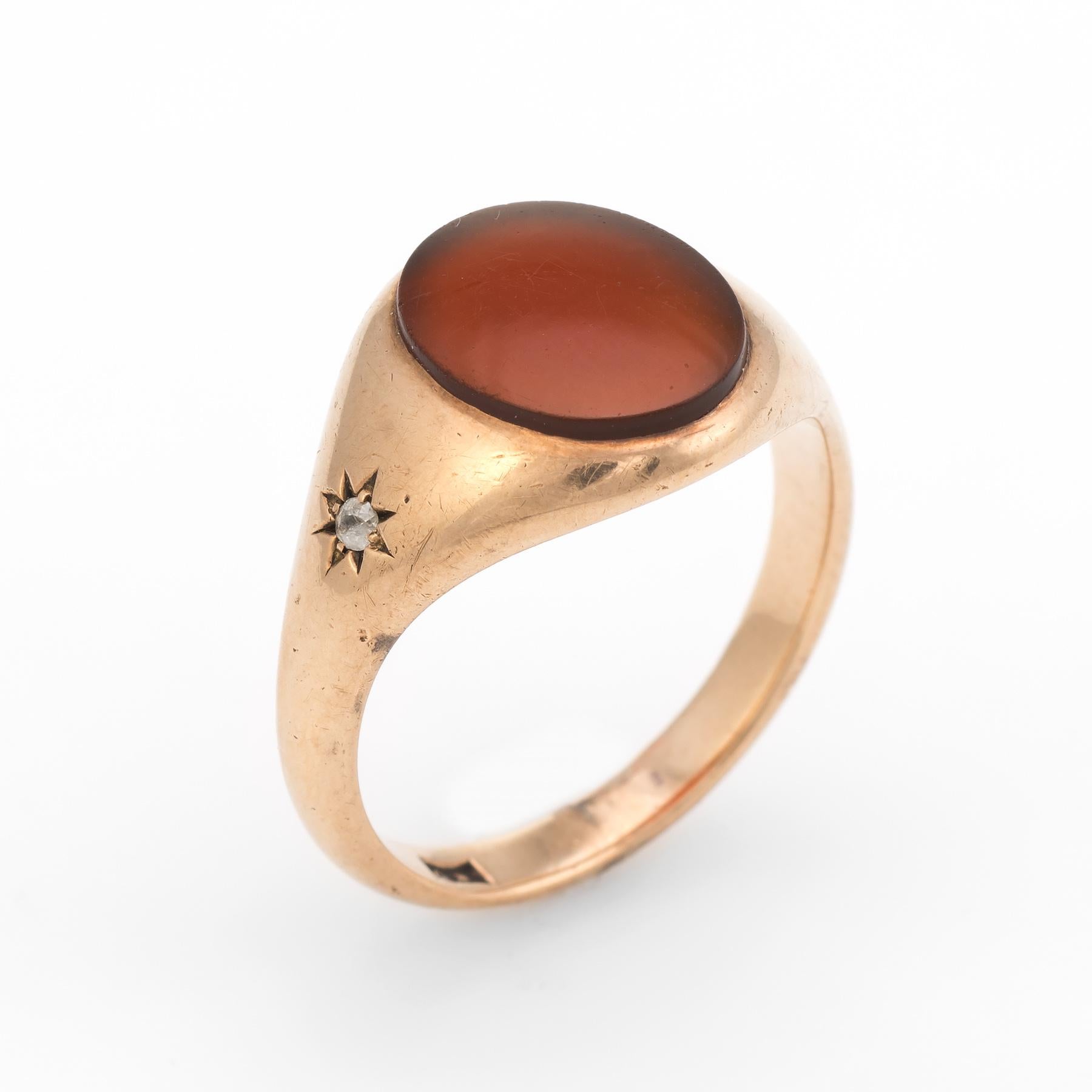 Finely detailed vintage Art Deco era ring (circa 1920s to 1930s), crafted in 10 karat rose gold. 

Oval cut Carnelian measures 11.8mm x 10mm (estimated at 6.5 carats), accented with two estimated 0.01 carat old mine cut diamonds (0.02 carats total