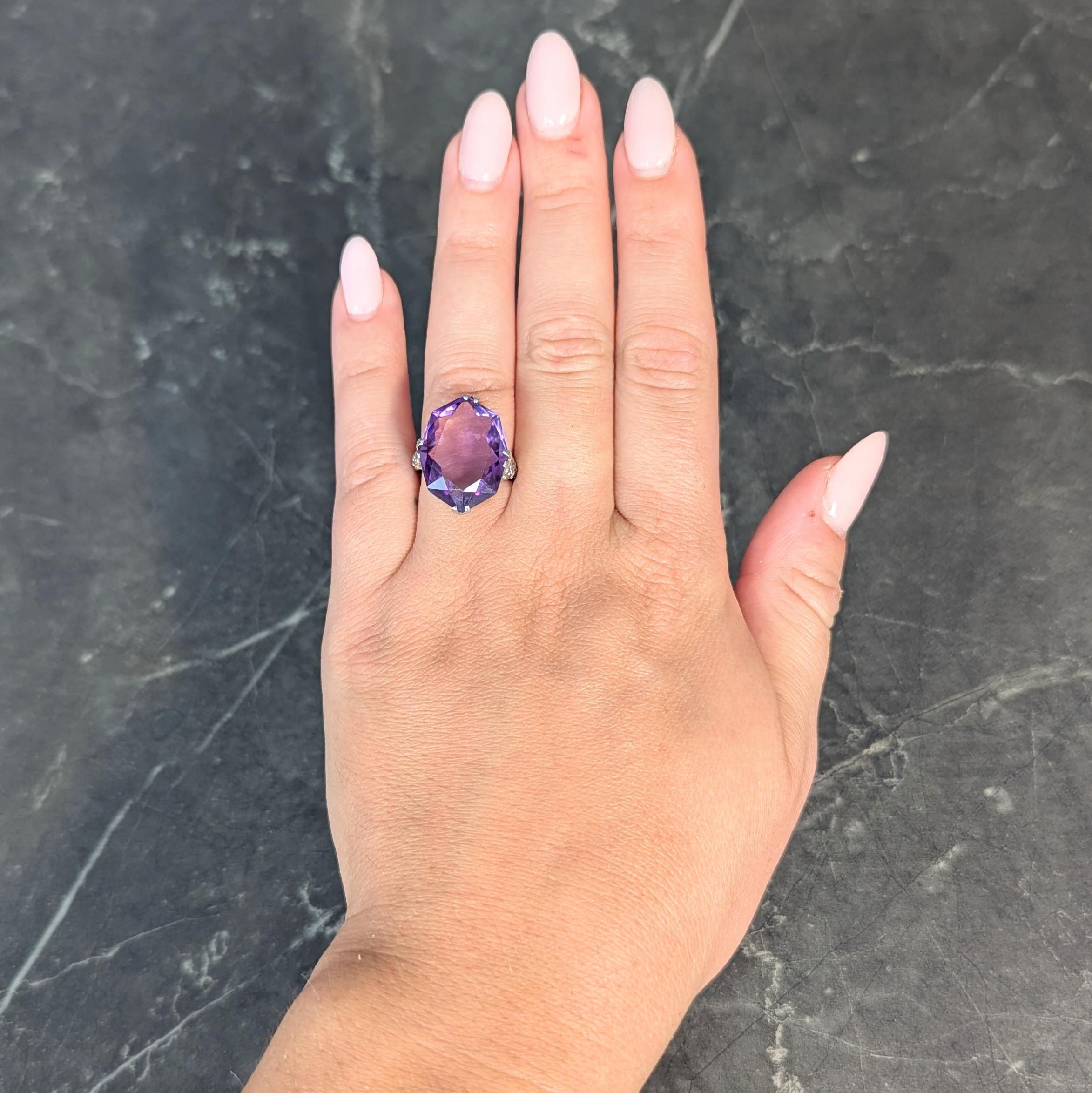 Centering a mixed cut oval amethyst weighing approximately 11.12 carats 
Transparent medium purple in color and set with split prongs
Featuring a pierced lace-like gallery and milgrain detail
Decorated with orange blossom motif appliqué
With foliate