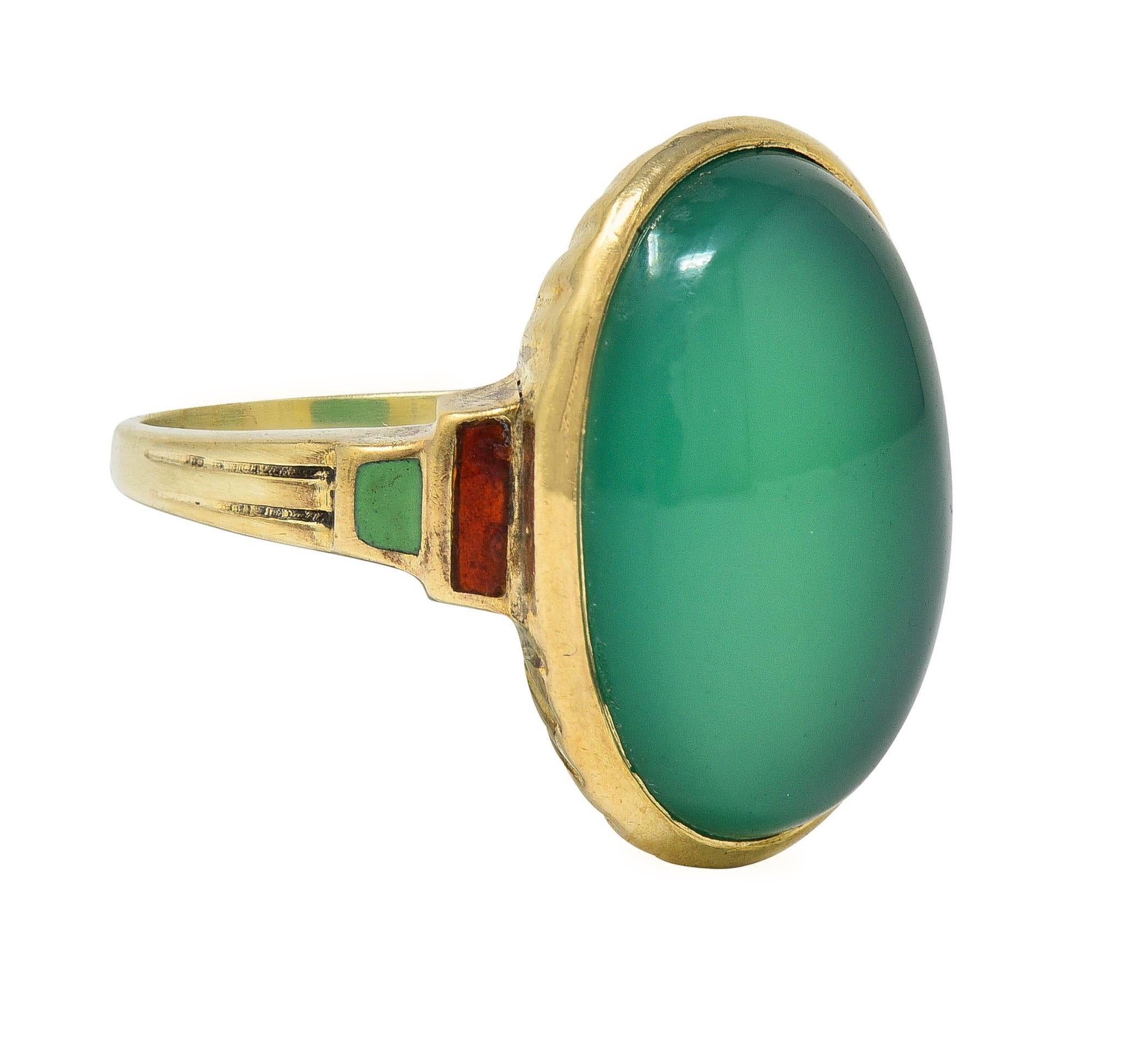 Centering an oval shape chrysoprase cabochon measuring 12.5 x 17.8 mm 
Translucent vibrant bluish-green in color with subtle chatoyancy
Bezel set with a fluted gallery and flanked by stepped shoulders
Inlaid with transparent orange and opaque light
