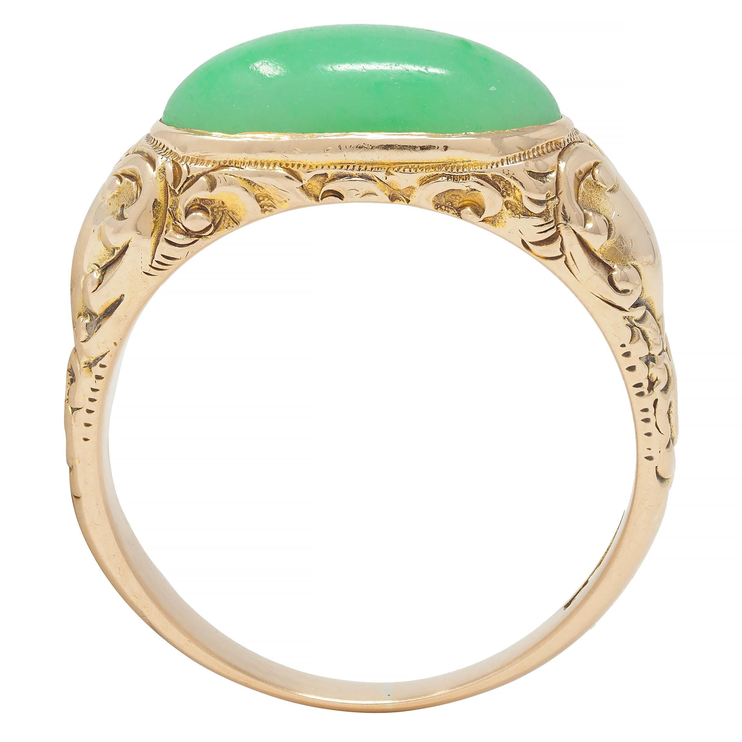 Centering an oval-shaped jade cabochon measuring 7.5 x 15.5 mm 
Translucent pastel green with subtle mottling flush set east to west
Flanked by engraved cartouche motif shoulders
Featuring an engraved scroll motif surround 
With high polish