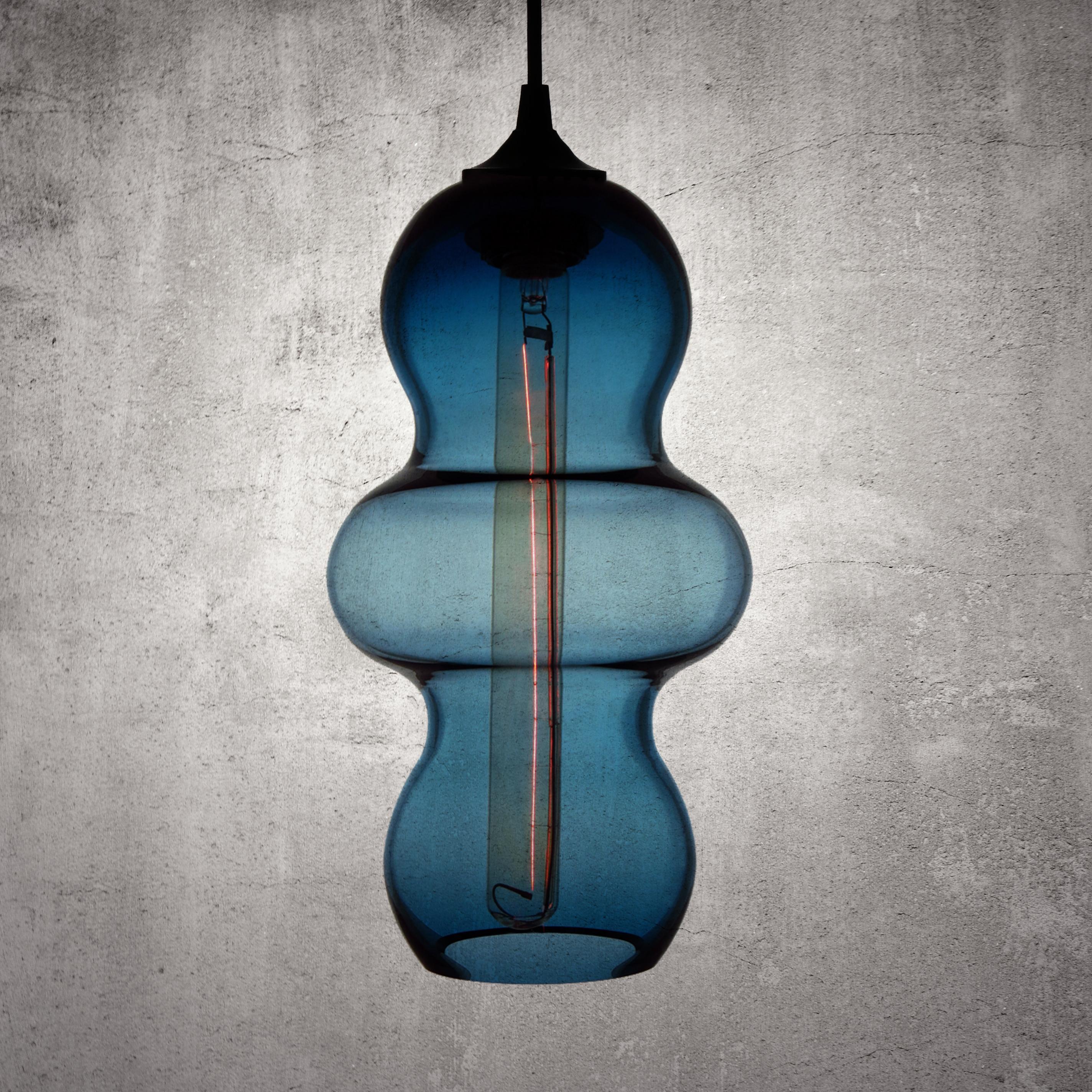 The Tamarindo contemporary glass pendant lamp is a contemporary interpretation of the tamarind fruit. Encapsulating its characteristics, the Tamarindo is sleek, curvaceous and light, hanging effortlessly with its long elongated form juxtaposed by a