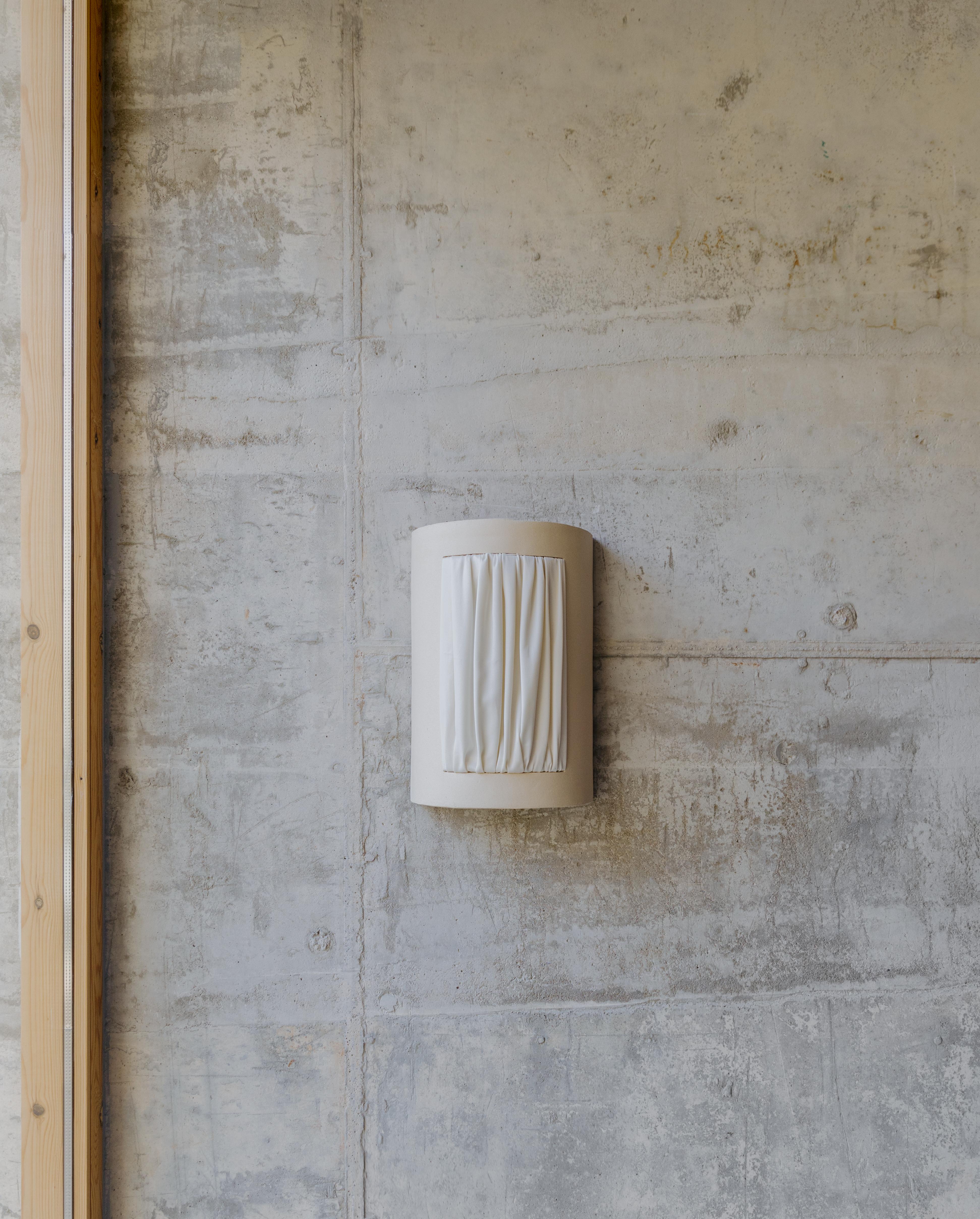 Almond Medium Istos Wall Light by Lisa Allegra
Dimensions: D 13x W 23 x H 34 cm.
Materials: Piece in ceramic and Dedar fireproofed fabric color Ivory.

Also available in different colored fabric: ivory, nude, salvia, senape or beige. Please contact