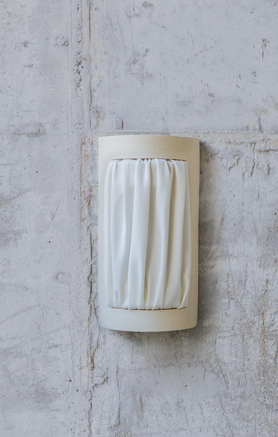 Almond Smaill Istos Wall Light by Lisa Allegra
Dimensions: D 7.5 x W 11.5 x H 21 cm.
Materials: Piece in ceramic and Dedar fireproofed fabric color Ivory.

Also available in different colored fabric: ivory, nude, salvia, senape or beige. Please