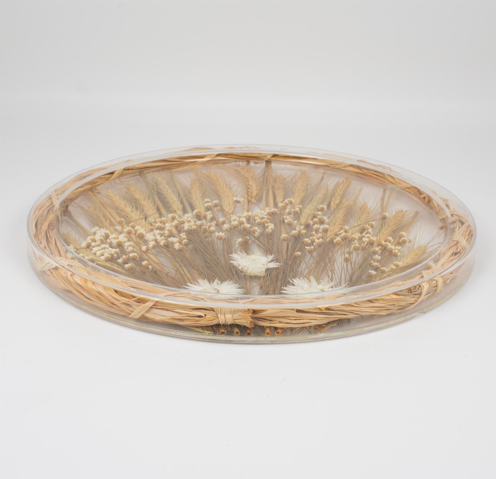 This is a lovely serving tray designed by Alpac Creations, France, in the 1980s. This board or platter has a rounded shape and raised edges. 
The platter has a natural organic touch and is built with clear Lucite or plexiglass and genuine wheat and