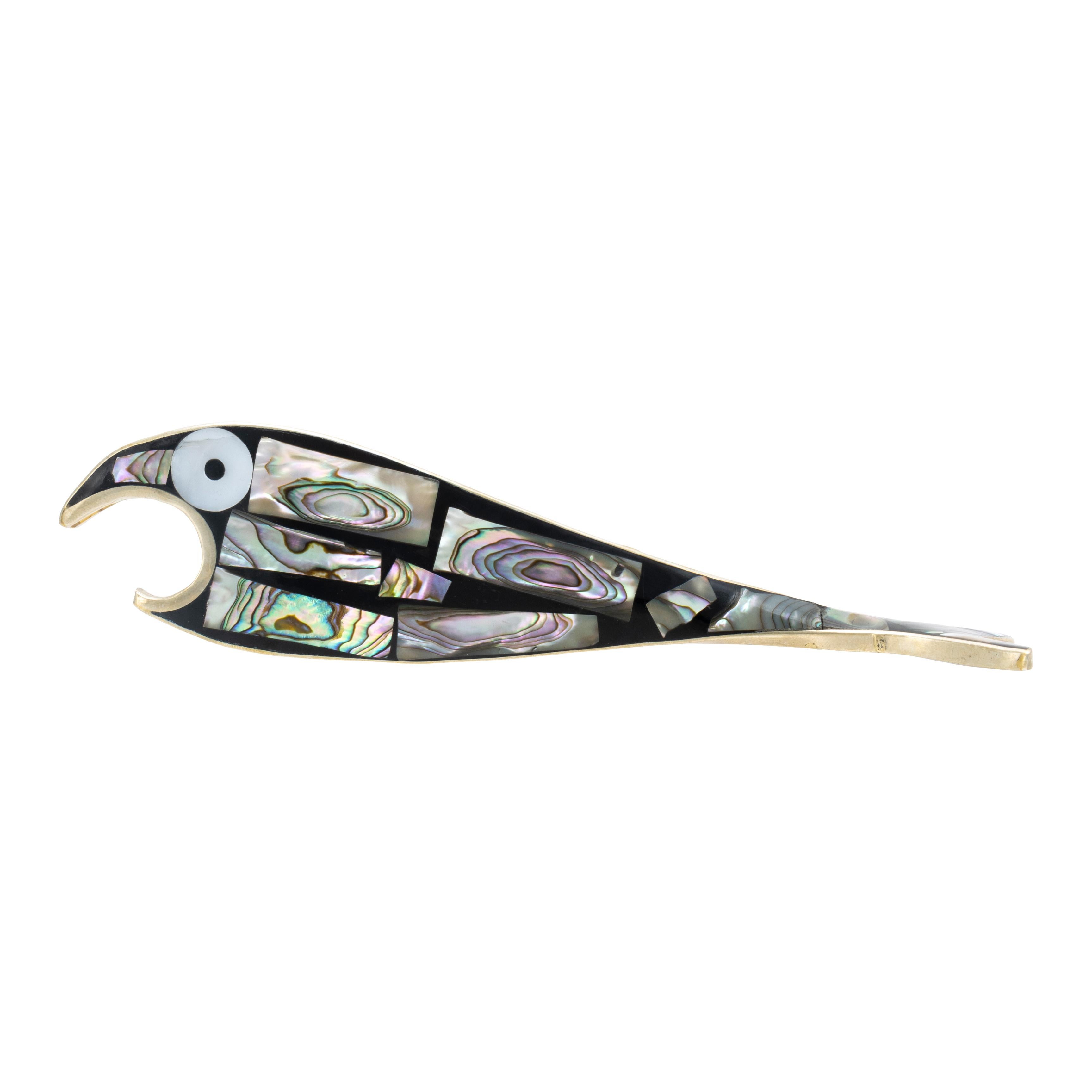 Apribottiglie a forma di pesce in argento Alpaca. Caratterizzato da un intarsio di abalone blu del Pacifico, che contrasta piacevolmente con lo sfondo nero del pezzo e da grandi occhi di conchiglia bianchi e neri. Il suo corpo è piatto con una bocca
