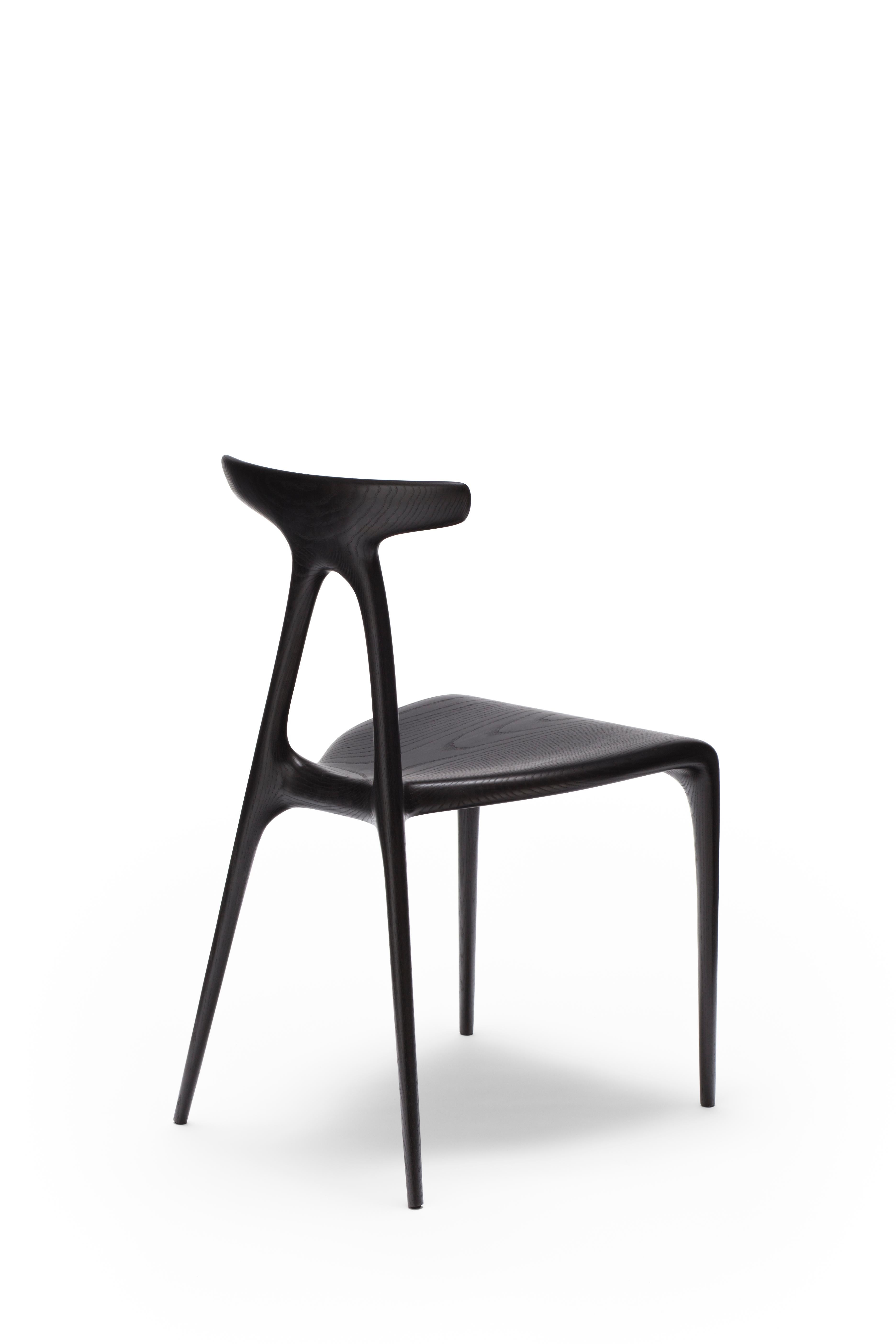 Une chaise empilable polyvalente contemporaine en bois massif, produite à l'aide des dernières technologies de production de meubles en bois façonné. Le design s'enorgueillit d'un geste architectural fort qui confère à la chaise sa force inhérente :