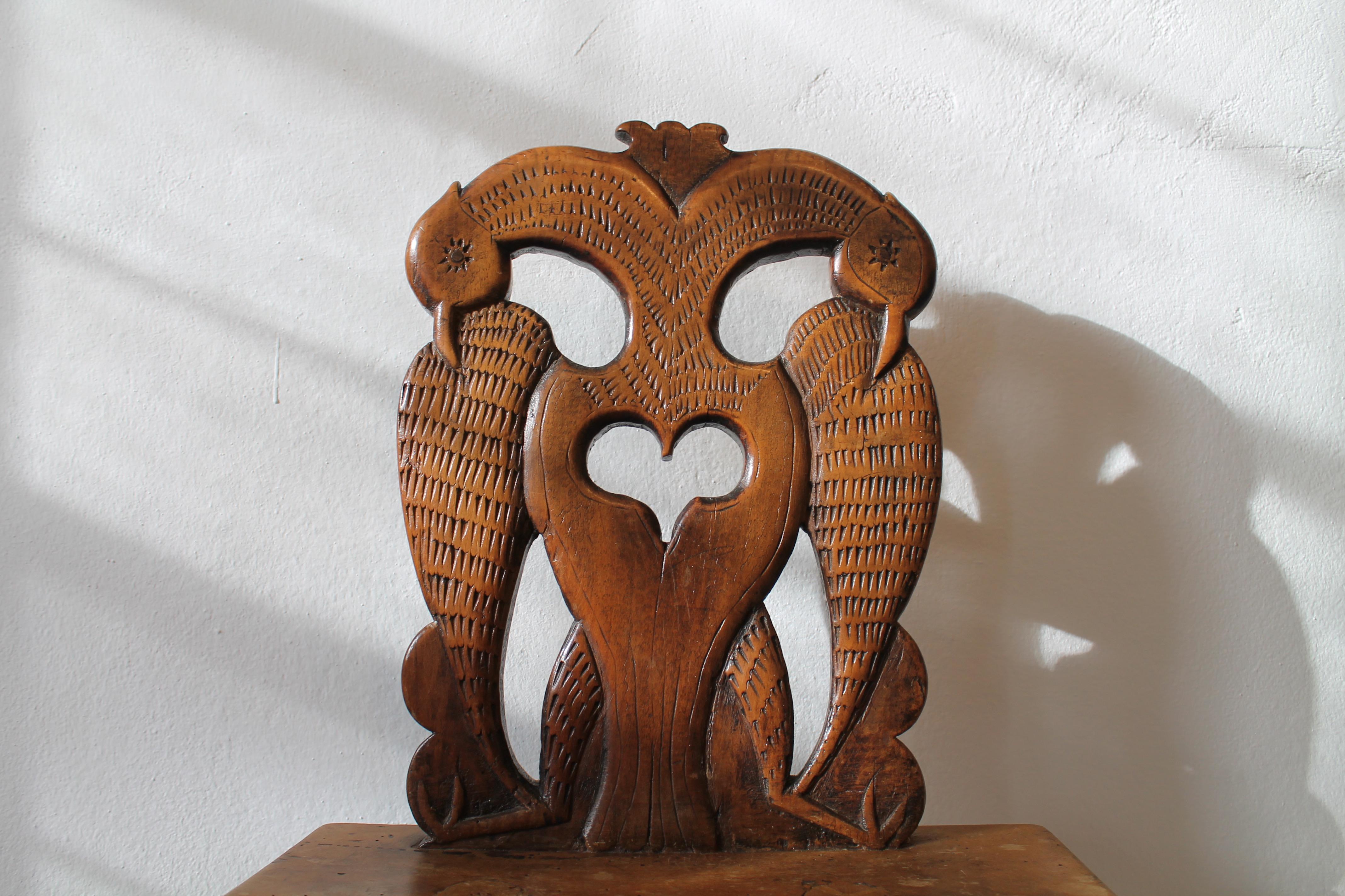 The present piece is an unusual board chair made of walnut from the Alpine region. It is not a simple peasant chair, as evidenced by the particularly ornately carved birds that adorn the backrest. The chair was made in the 18th century in Bavaria or
