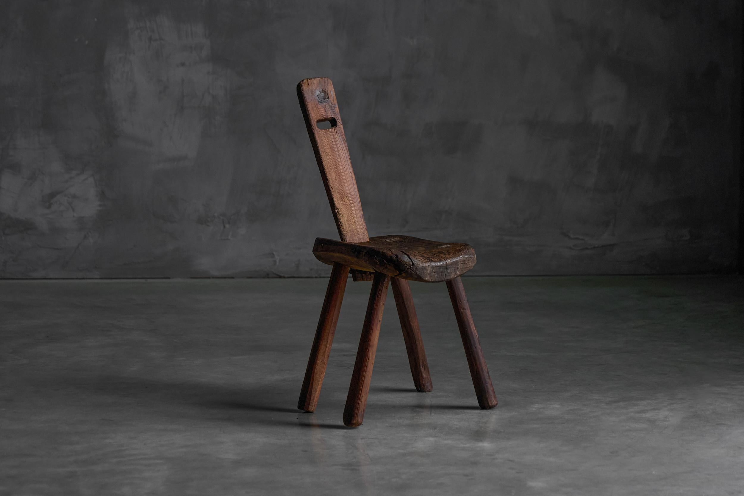 Ce fauteuil alsacien du XIXe siècle présente un cadre en bois teinté foncé, typique de l'artisanat régional. Le dossier comprend deux lattes horizontales surmontées d'épis de faîtage arrondis, ce qui ajoute à son charme rustique. Les accoudoirs