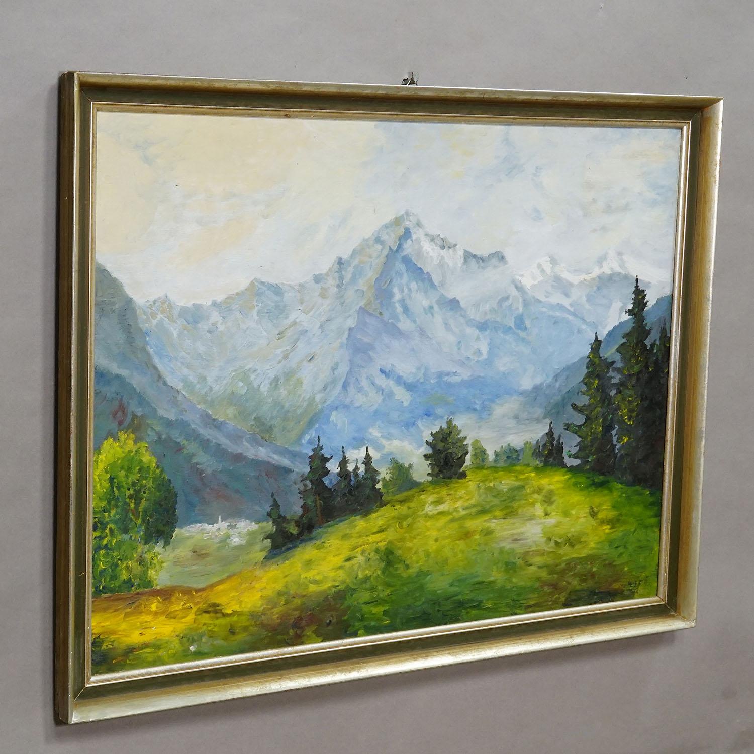 Alpine Landscape Painting with Meadow, Trees and Mountains

A large magnificent landscape painting in a golden wooden frame. The scene shows a mountainous landscape with a bright, green meadow in the foreground, dark green forests and with towering