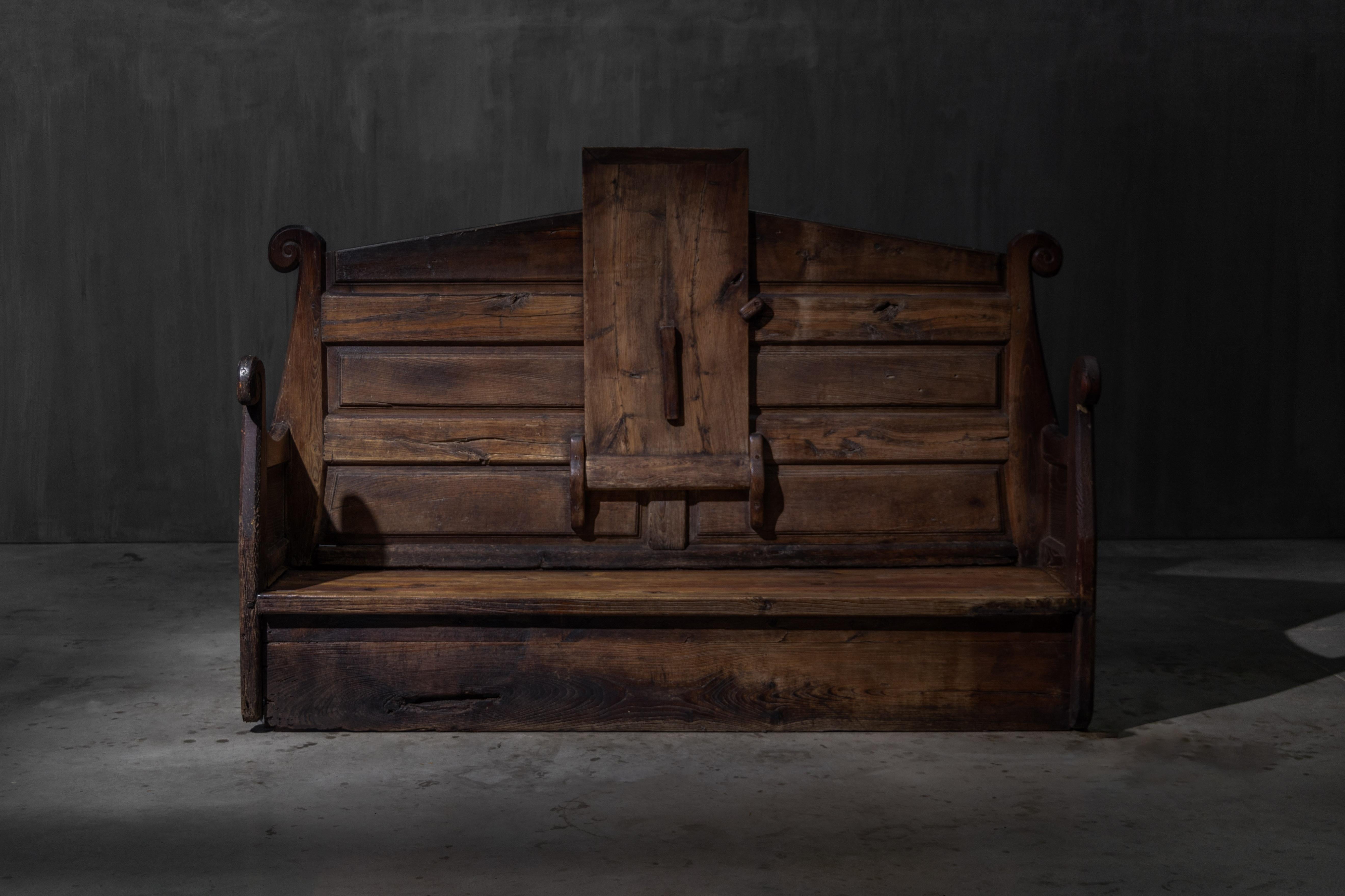 Banc monastique alpin rare et sculptural du XIXe siècle, fabriqué à la main en bois massif avec une patine riche et usée par le temps. Cette pièce multifonctionnelle a probablement été utilisée dans un cadre communautaire ou ecclésiastique dans les