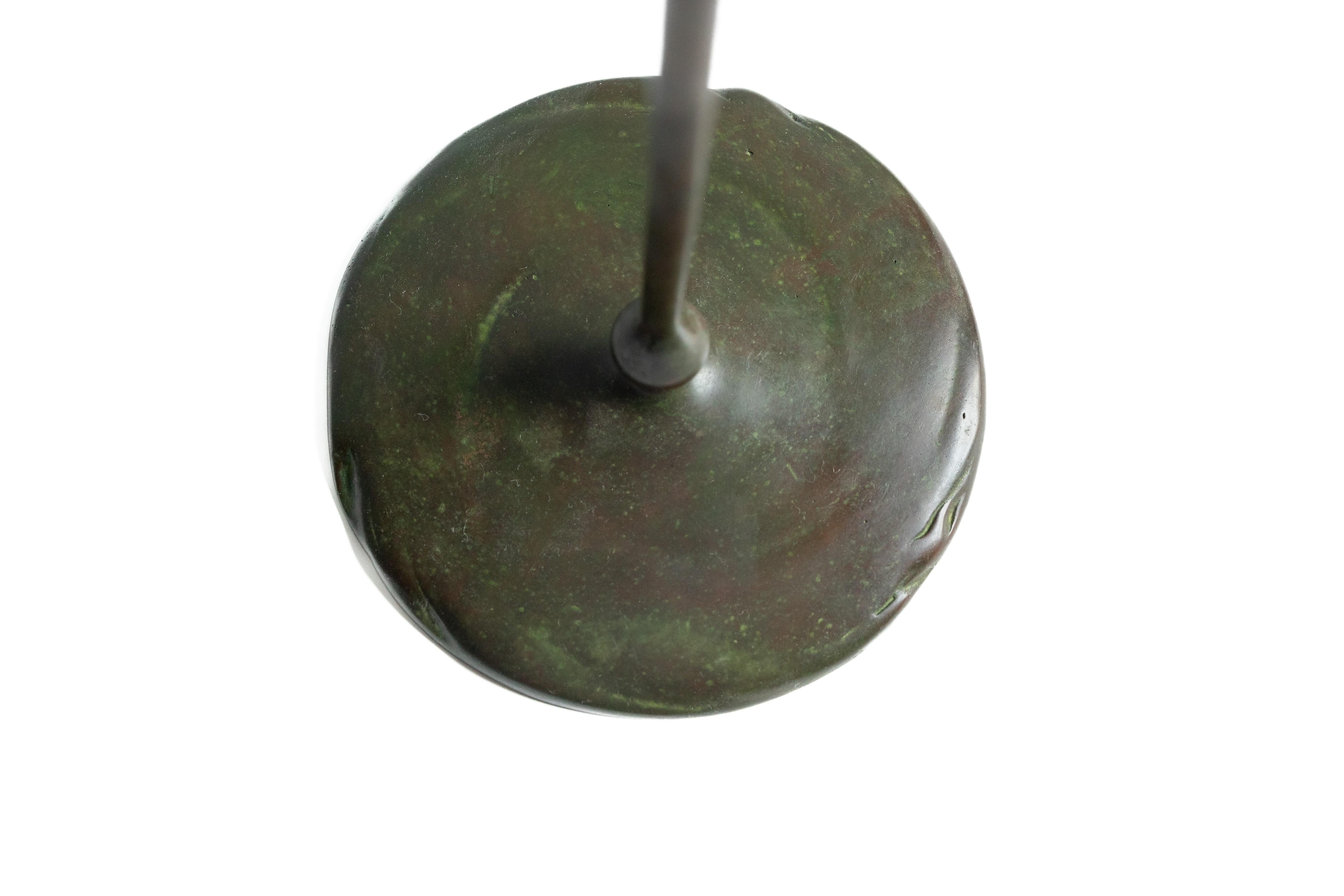 A  coppia di candelieri alti e sottili in stile Art Nouveau, in bronzo patinato verde e scuro.
Un grande disco con bordo increspato e texture vorticosa funge da piede della composizione, da cui parte un gambo rigido, decorato da un piccolo bulbo