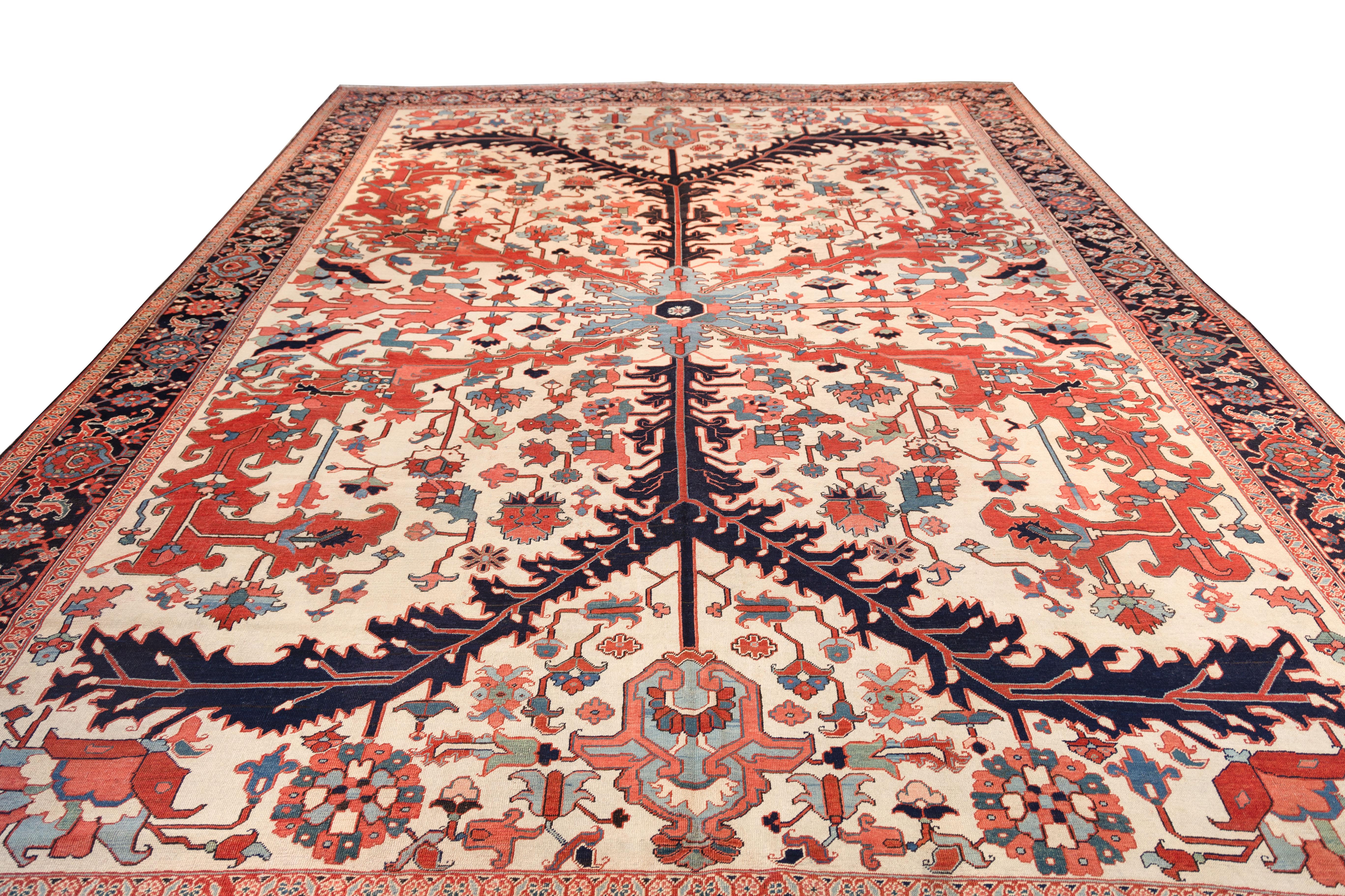 Un médaillon central à branches sur fond ivoire, avec des motifs floraux géométriques de couleur rouille, bleue, verte et noire. La large bordure marine comprend un motif répété de rosettes et de rinceaux de vigne. Le dessin est symétrique et