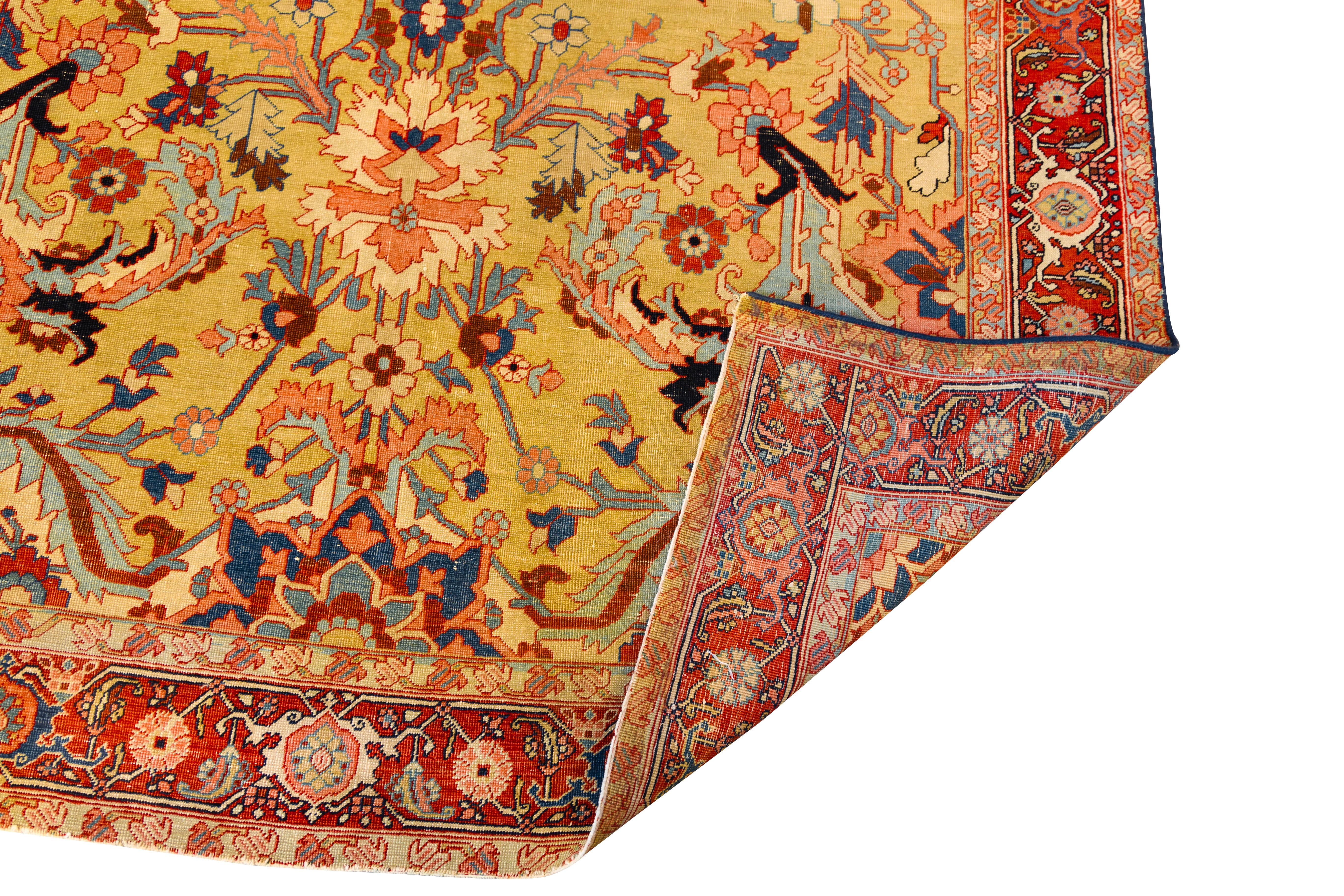 19th-century Persian Serapi rug featuring a central medallion design on a golden-yellow field. The composition includes angular floral and vine motifs in shades of red, blue, ivory, and black. A wide red border frames the central design, decorated