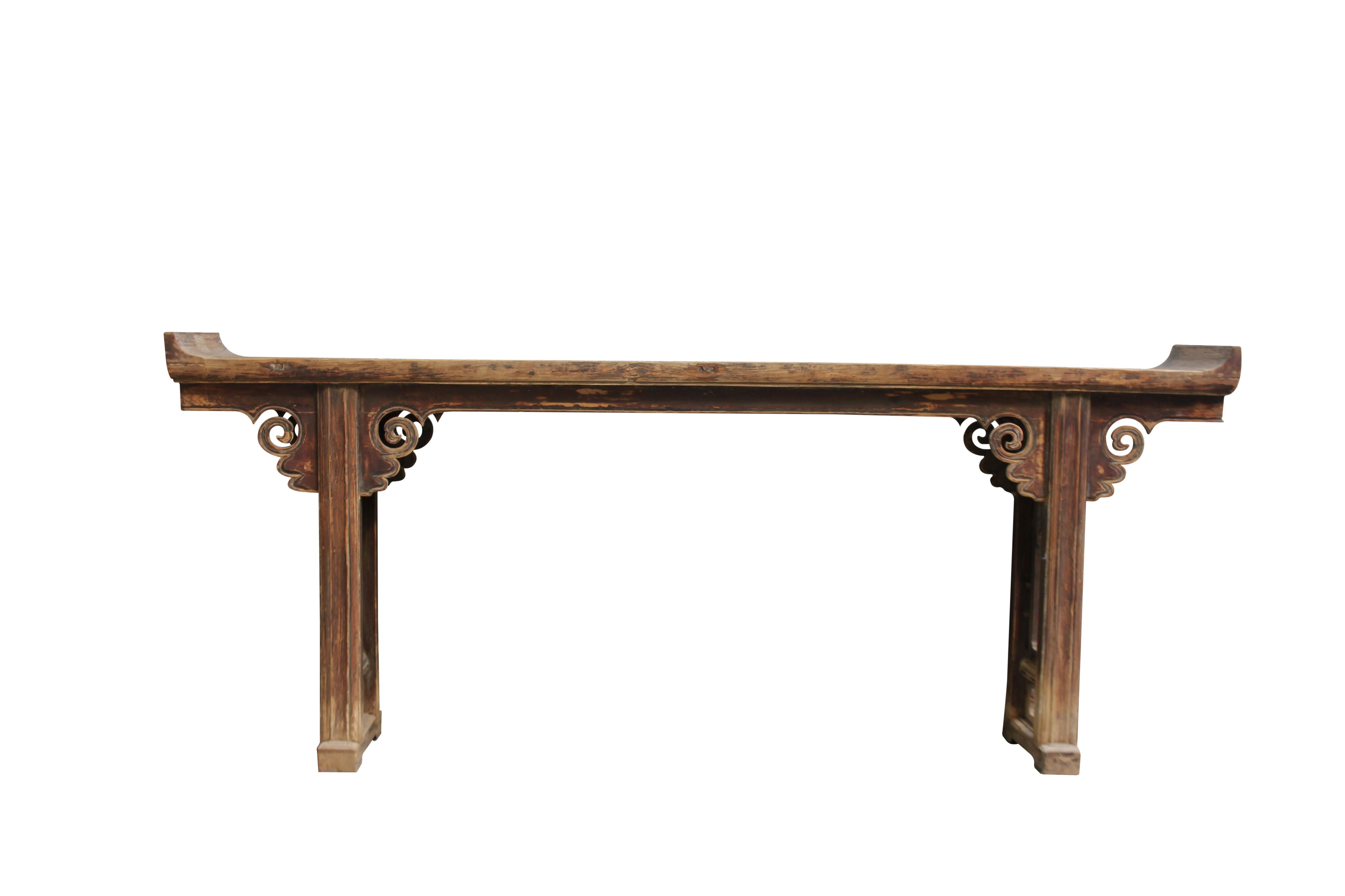 This Chinese altar table with everted ends features carved cloud spandrels on both front and back and open carved panel legs. With hand carved spandrels and panel legs, beautiful aged top, and everted ends, this console table will make an impressive