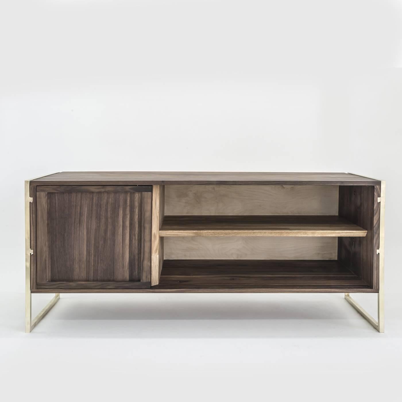 Raised on a polished brass frame, the essential Silhouette of this impeccable sideboard merges style with functionality. Entirely handcrafted of walnut wood, the structure appears to be suspended between the brass supports that hold it via slot-in