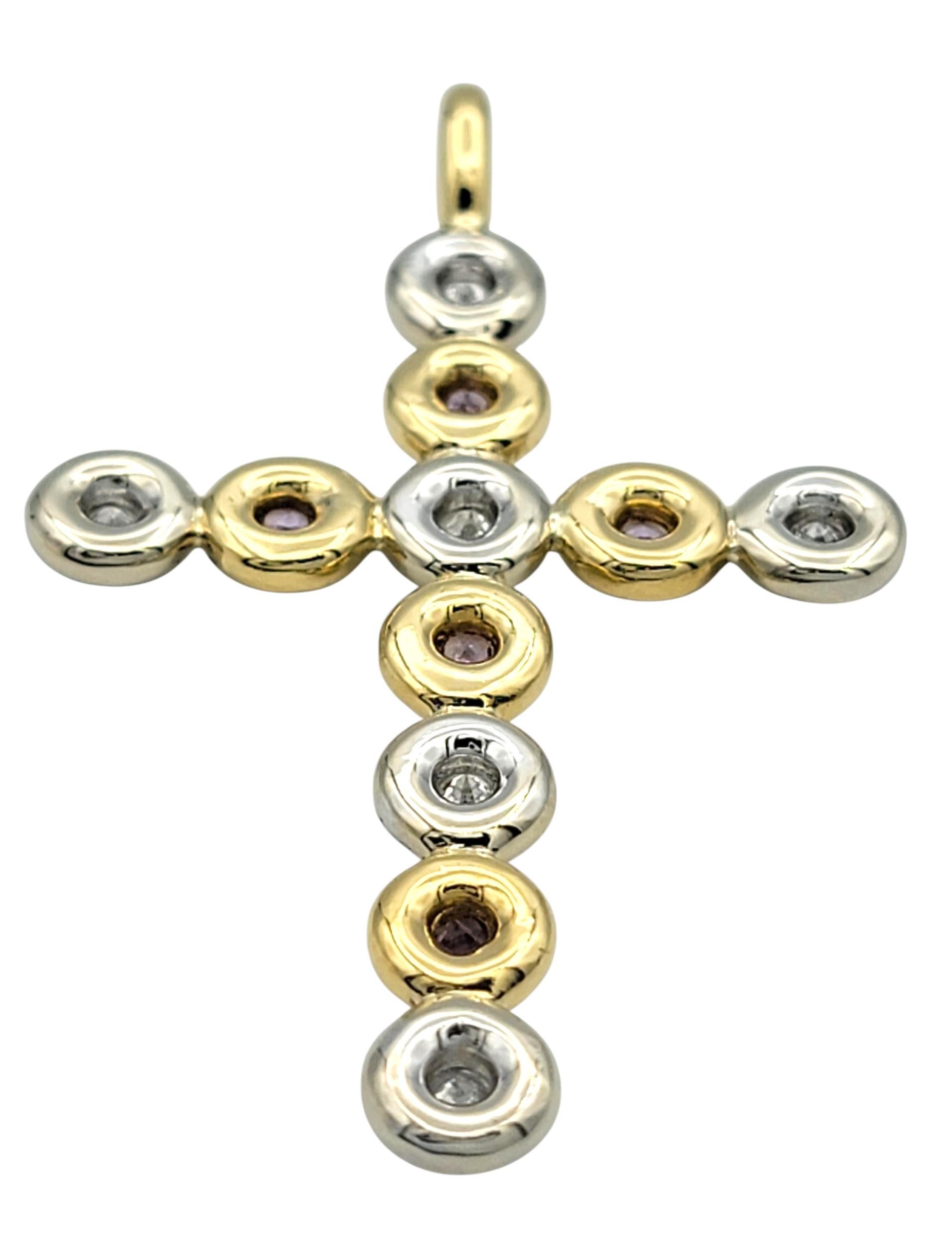 Questo elegante ciondolo a forma di croce è realizzato in oro giallo e bianco a 18 carati e unisce la bellezza classica a un raffinato scintillio. Il ciondolo è disegnato con un'alternanza di zaffiri rosa naturali e diamanti rotondi taglio