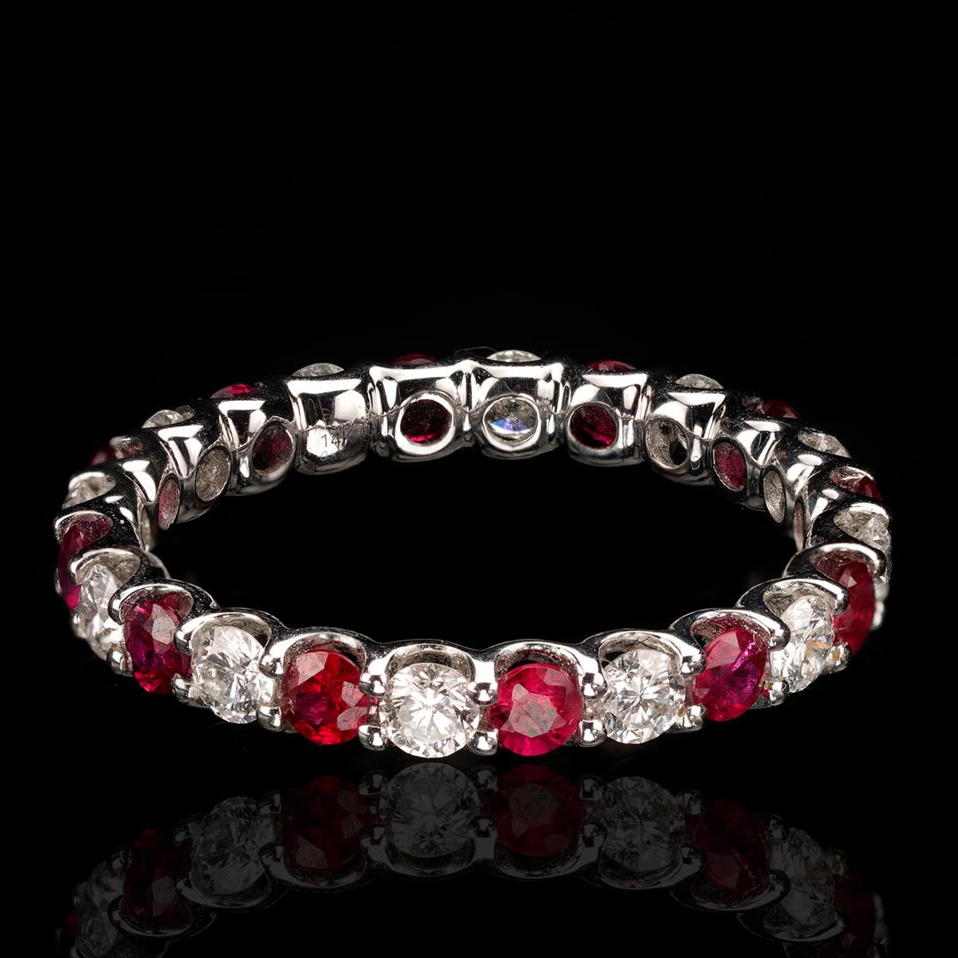This simply designed yet impactful eternity band features sparkling white diamonds and contrasting rich red rubies set alternating all the way around a 14 karat white gold band. With 12 round rubies totaling 0.81 carats and 12 diamonds totaling 0.64