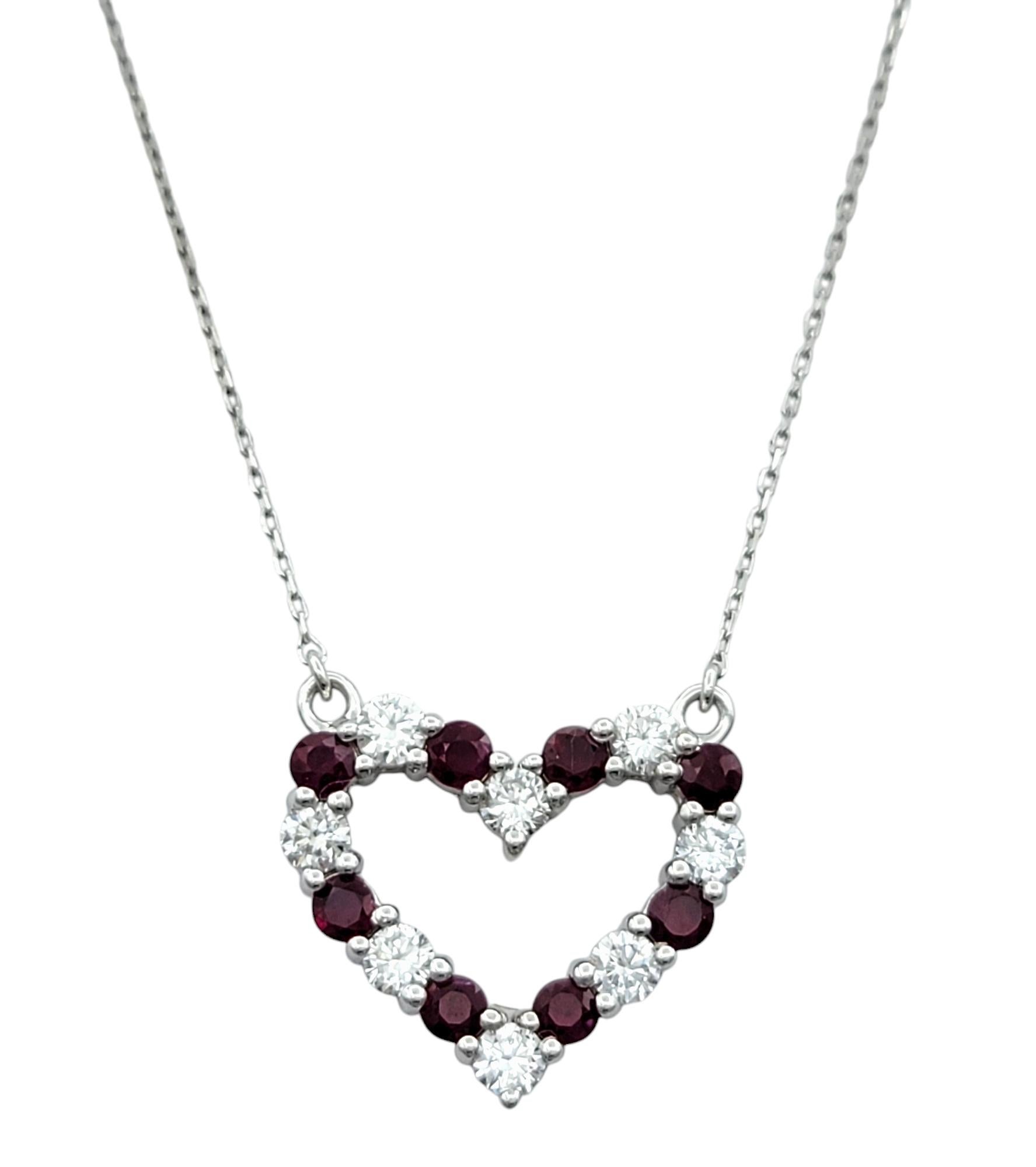 Questa squisita collana con ciondolo a cuore aperto è una vera incarnazione dell'amore e dell'eleganza. Incastonato in un radioso oro bianco da 14 carati, il ciondolo presenta una splendida composizione di vibranti rubini a taglio rotondo che