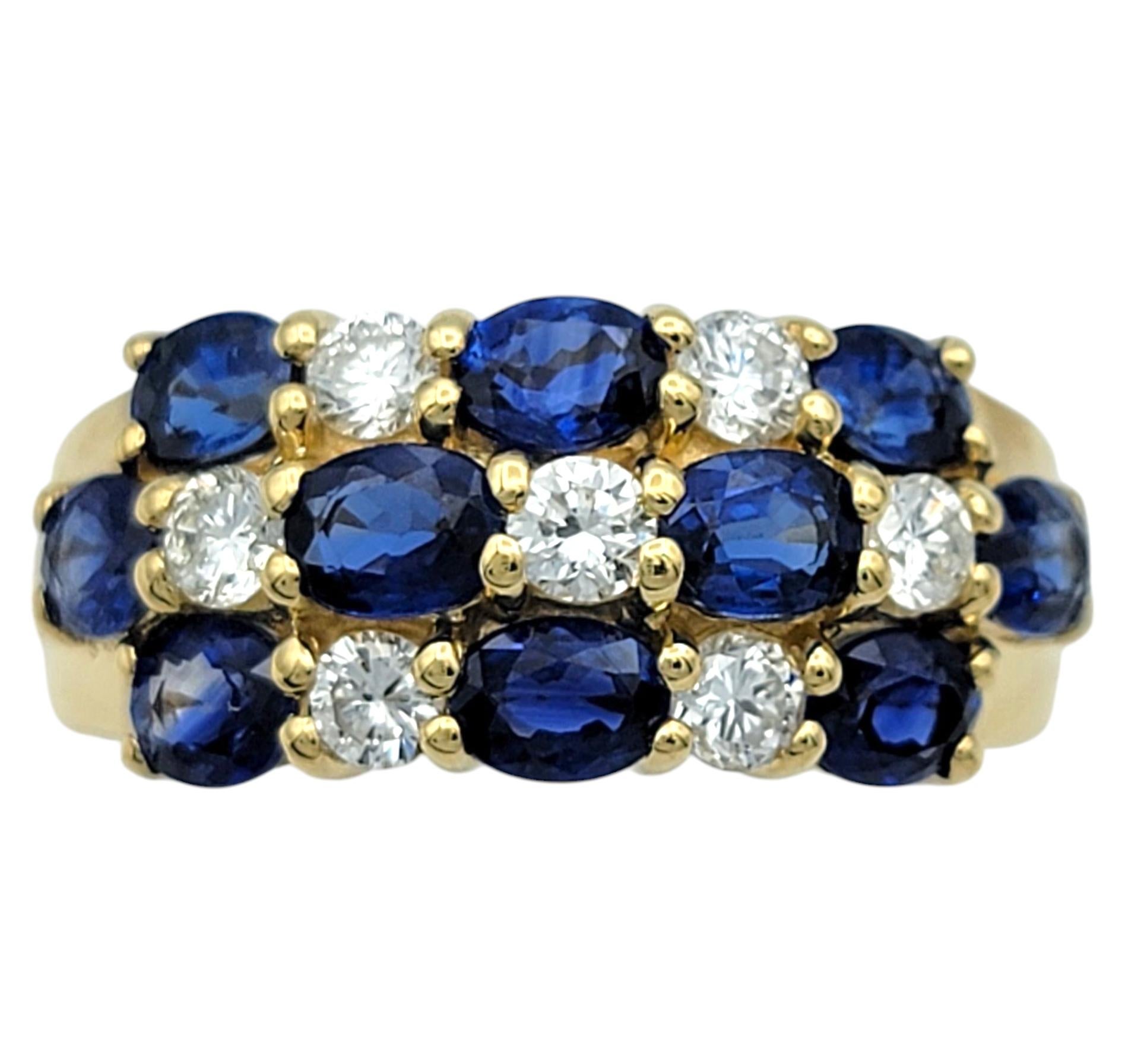 Ring Size: 6.5

This exquisite band ring is a stunning display of timeless elegance, featuring two rows of rich blue oval-cut sapphires set in a striking checkerboard pattern with brilliant round-cut diamonds. The sapphires’ deep, velvety hue