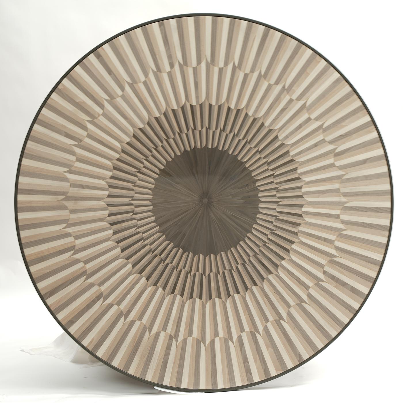 A mesmerizing pattern obtained with minute contrasting wooden inlays characterizes this exclusive coffee table. Veneered in Bolivar wood, the wide round top reveals a truly hypnotizing flair, while the rest of the wooden structure gets enriched with