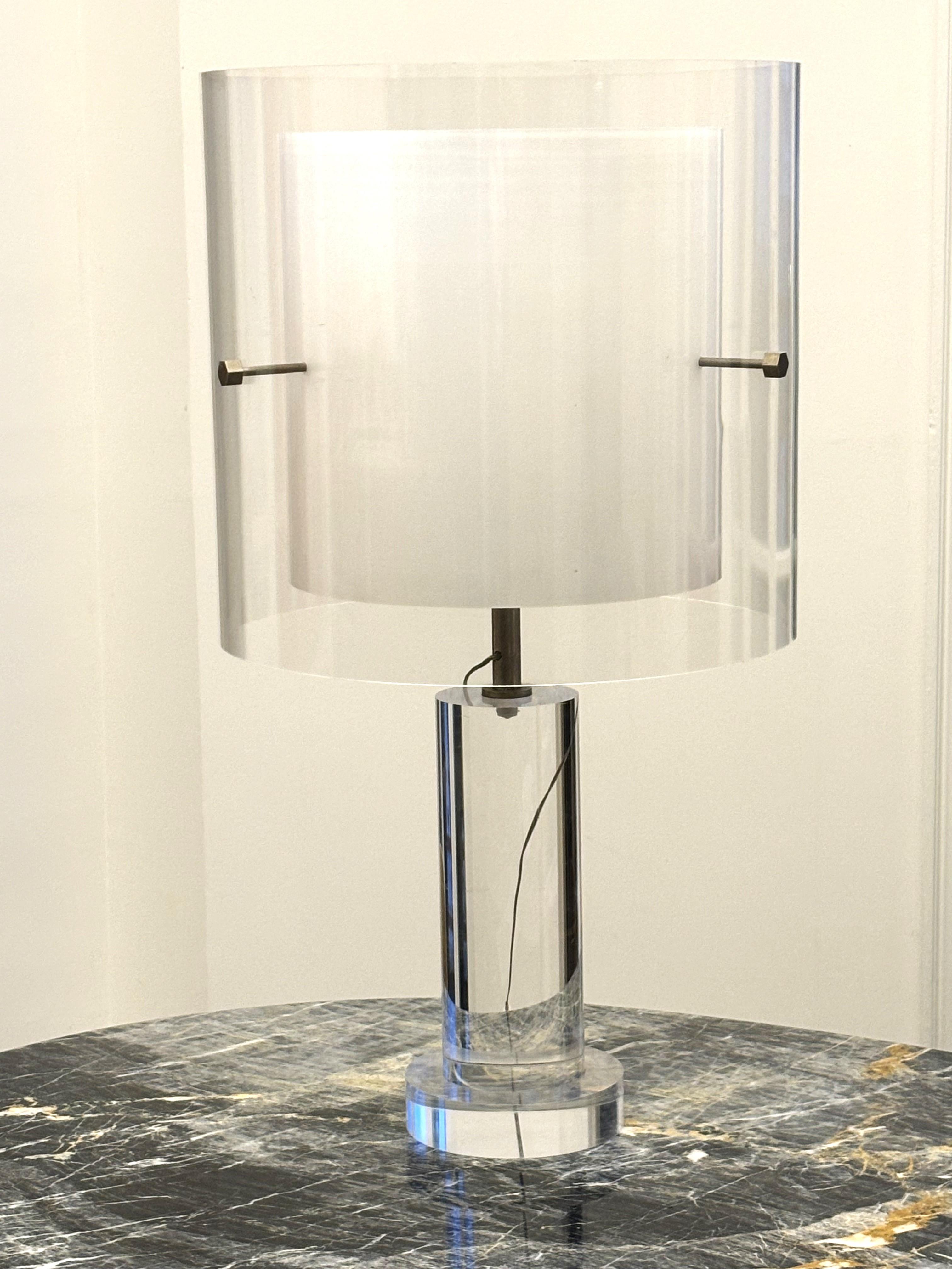 Italian table lamp with a double shade: a first white one softens the light, the second one is transparent and holds with an elegant metallic structure.
The base is made of a block of altuglass holding on a slightly larger second block of