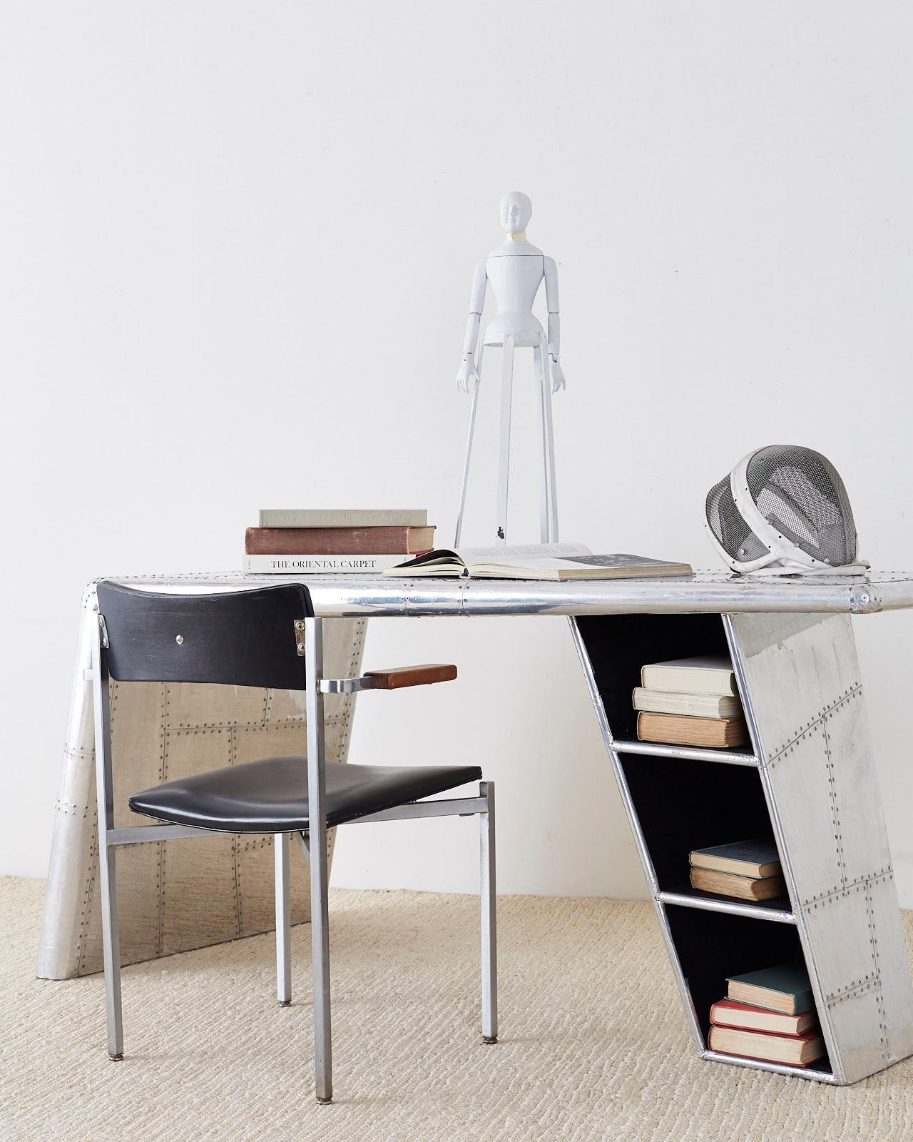 Polished aluminum aircraft aviation style jet wing writing table or desk. Inspired by World War II fighter planes. This wooden desk is covered in a patchwork of metal sheets and assembled using hundreds of mushroom rivets painstakingly attached by