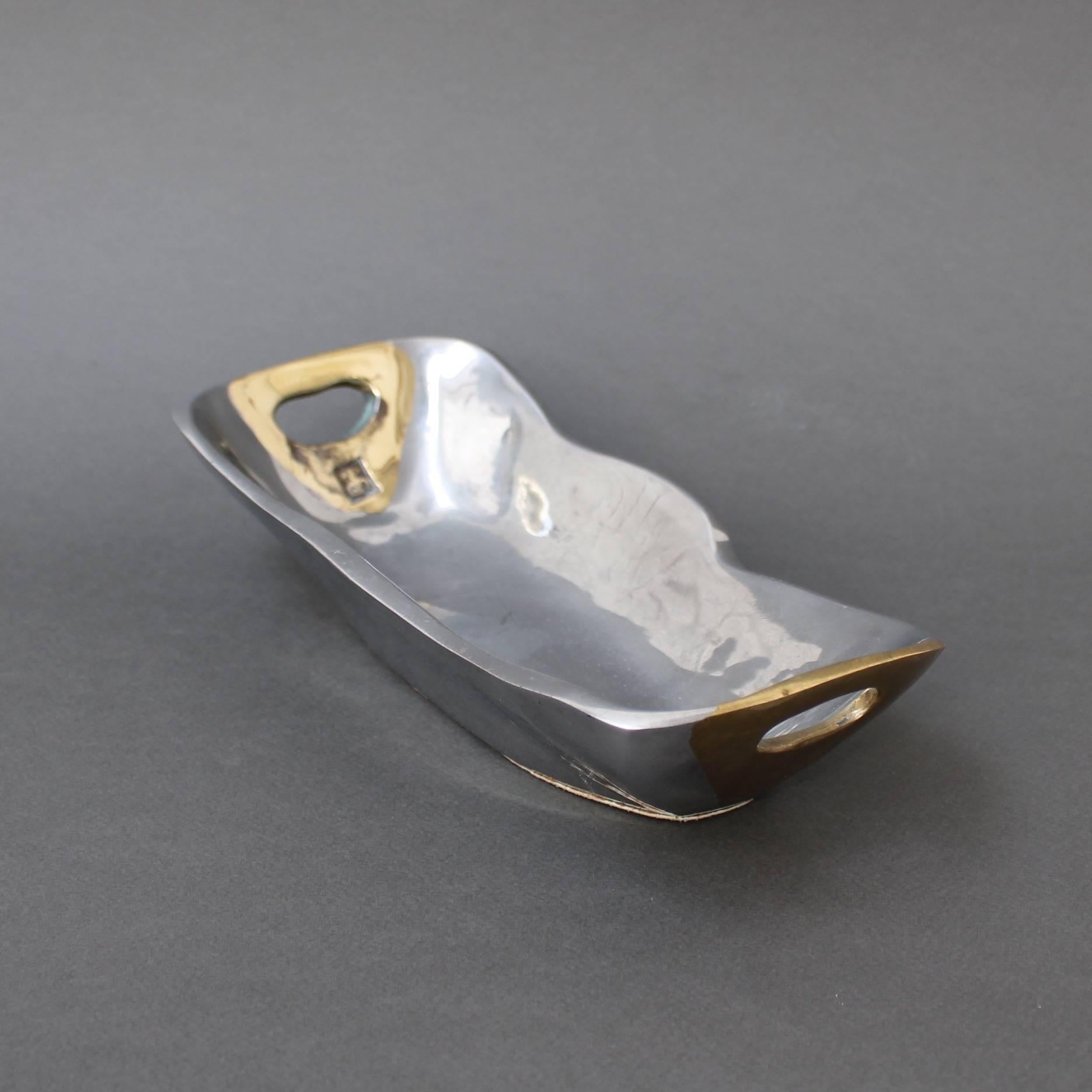 Aluminium and brass brutalist style tray by David Marshall, circa 1970s. In excellent vintage condition, this boat-shaped tray or vide-poche has retained much of its youthful appearance. The shiny aluminium forms the main structure and the brass