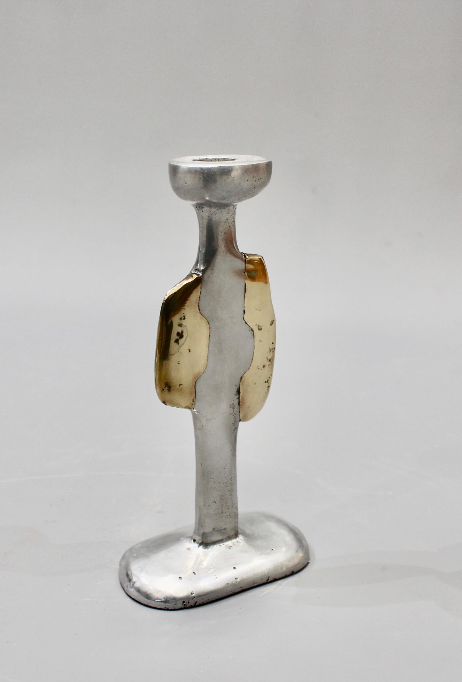 A single aluminium and brass candlestick by David Marshall (circa 1970s). Very unique piece which is all at once weighty and tactile, curvy and sensuous. The maker's signature is impressed on the aluminium surface near the brass side. The underside